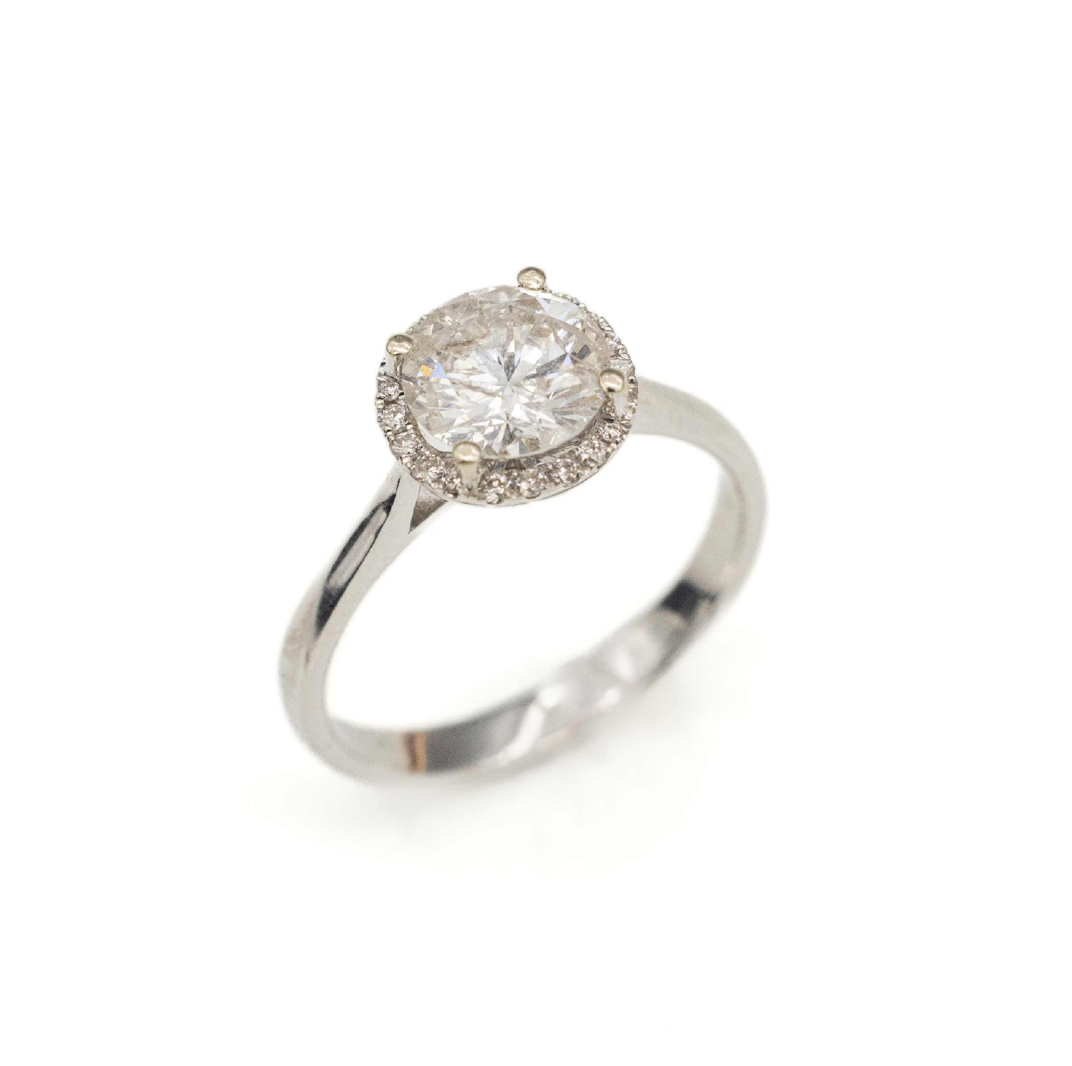 18 kt Gold Brillant-Ring, WG 750/000, mittig Brillant ca. 1.33 ct Weiß/p2, umgeben von 20 Brillanten zus. ca. 0.13 ct feines Weiß-Weiß/vs-si, RW ...