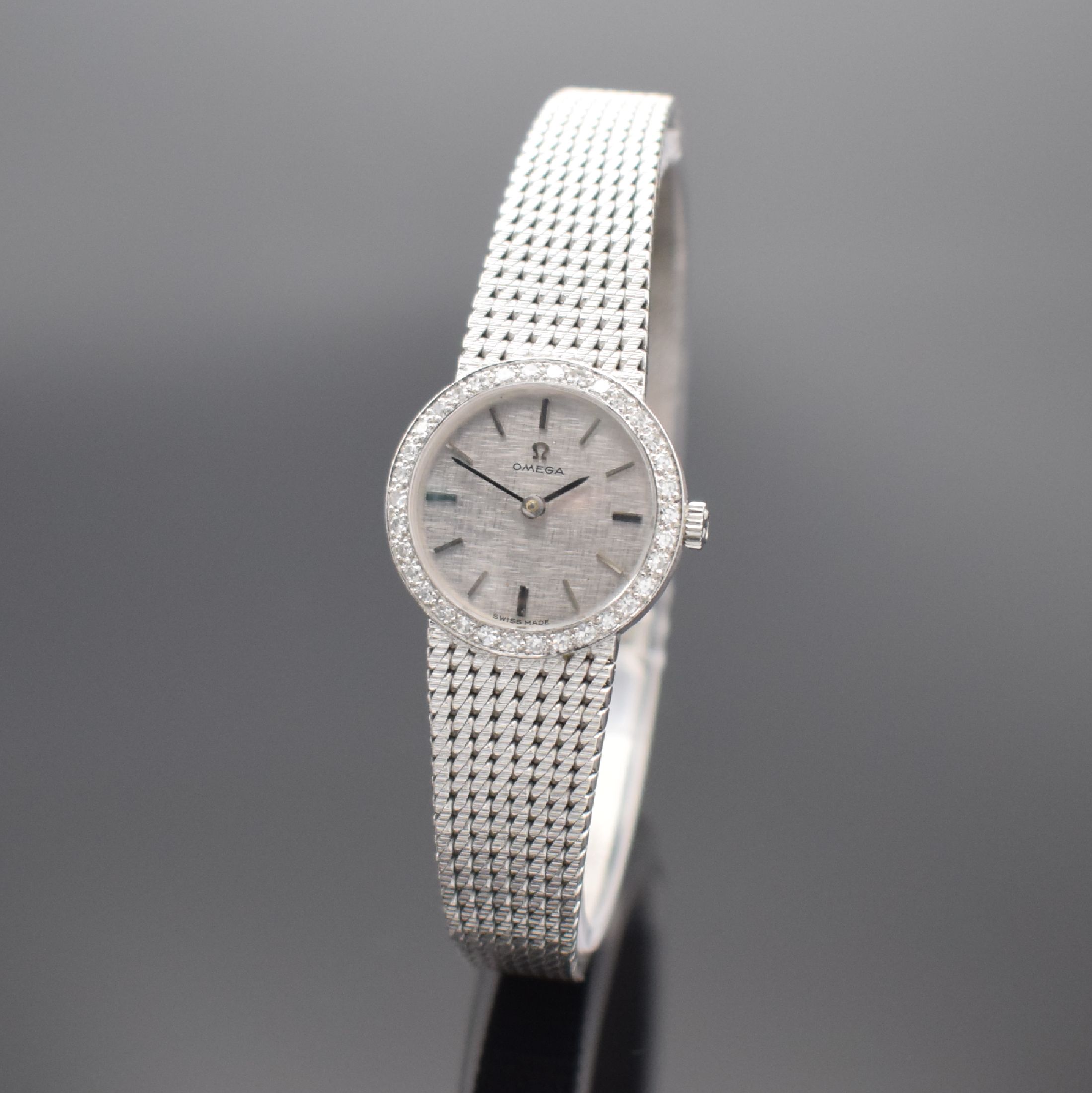 OMEGA Damenarmbanduhr in WG 750/000 mit Diamanten, Schweiz um 1967, Handaufzug, Boden aufgedr., Lünette aufw. m. Diamanten bes., silb. Zifferbl. m. ...