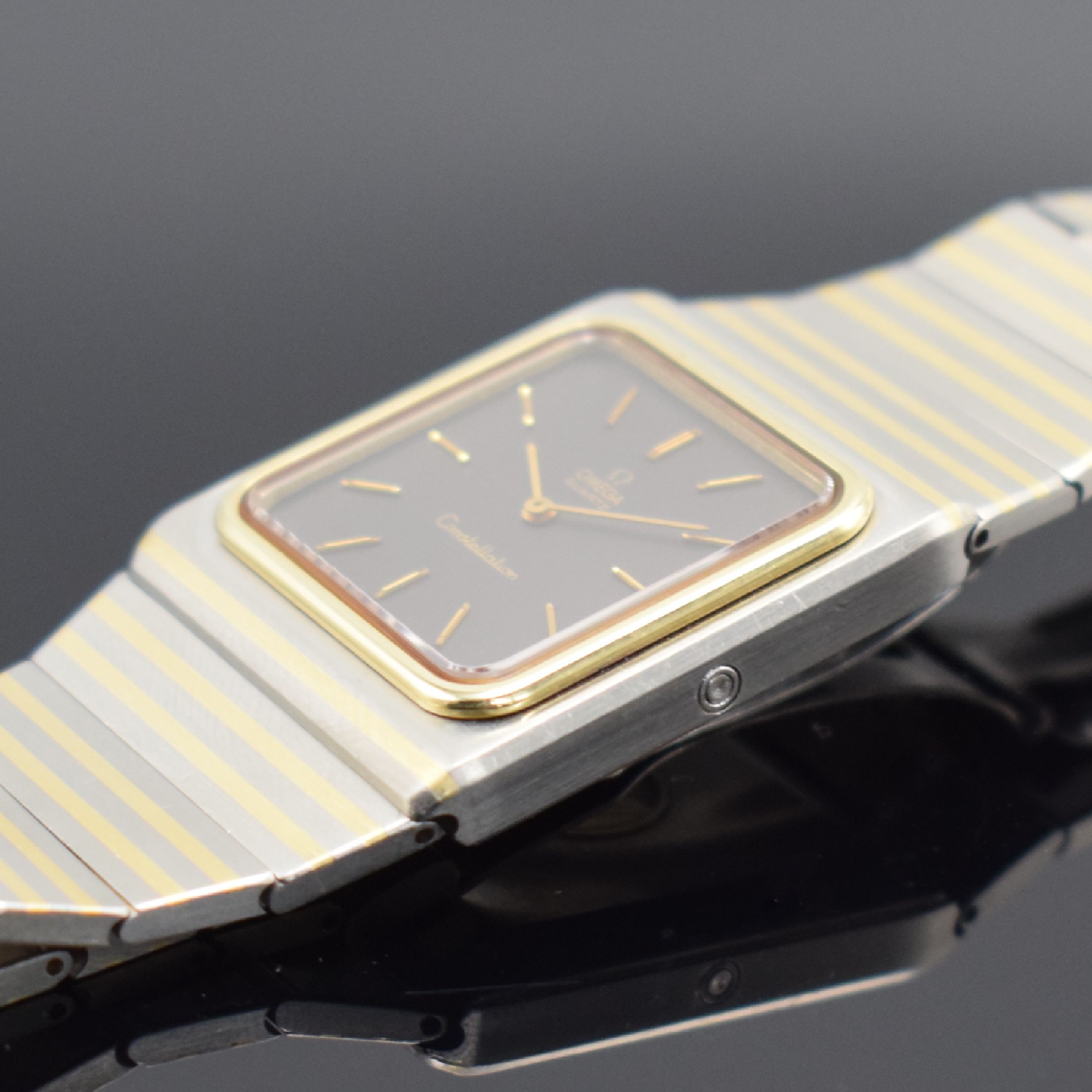 Detail c: OMEGA Constellation elegante Herrenarmbanduhr in Stahl/Gold, Schweiz um 1980, quarz, Ref. 395.0800, Geh. m. integriertem orig. Band & Faltschl., ...
