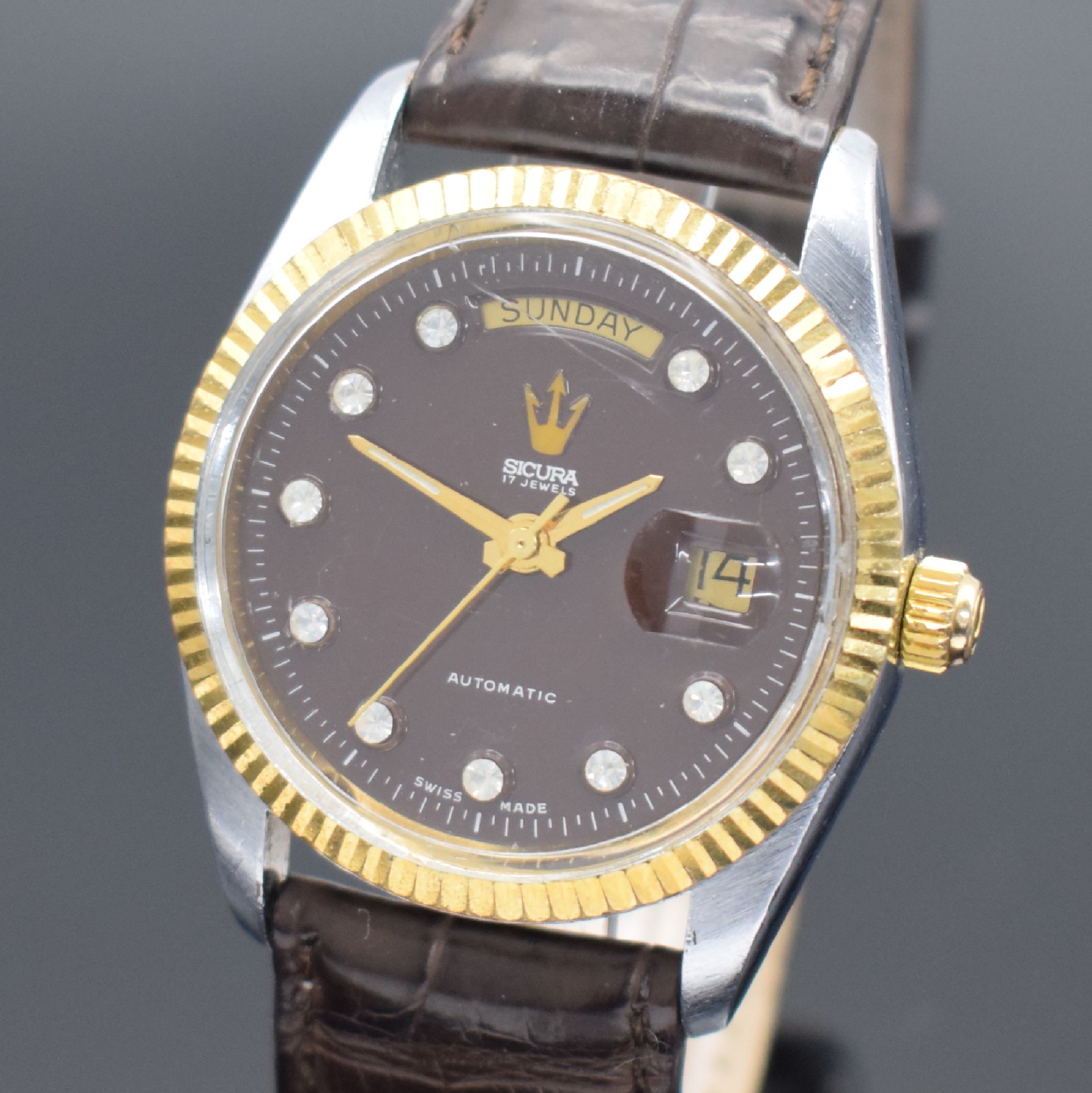Detail a: SICURA Herrenarmbanduhr Day-Date, Schweiz um 1975, verchr. Geh., Stahlboden verschr., geriffelte Lünette verg., bordeaux-farb. Zifferbl. m. gold. ...