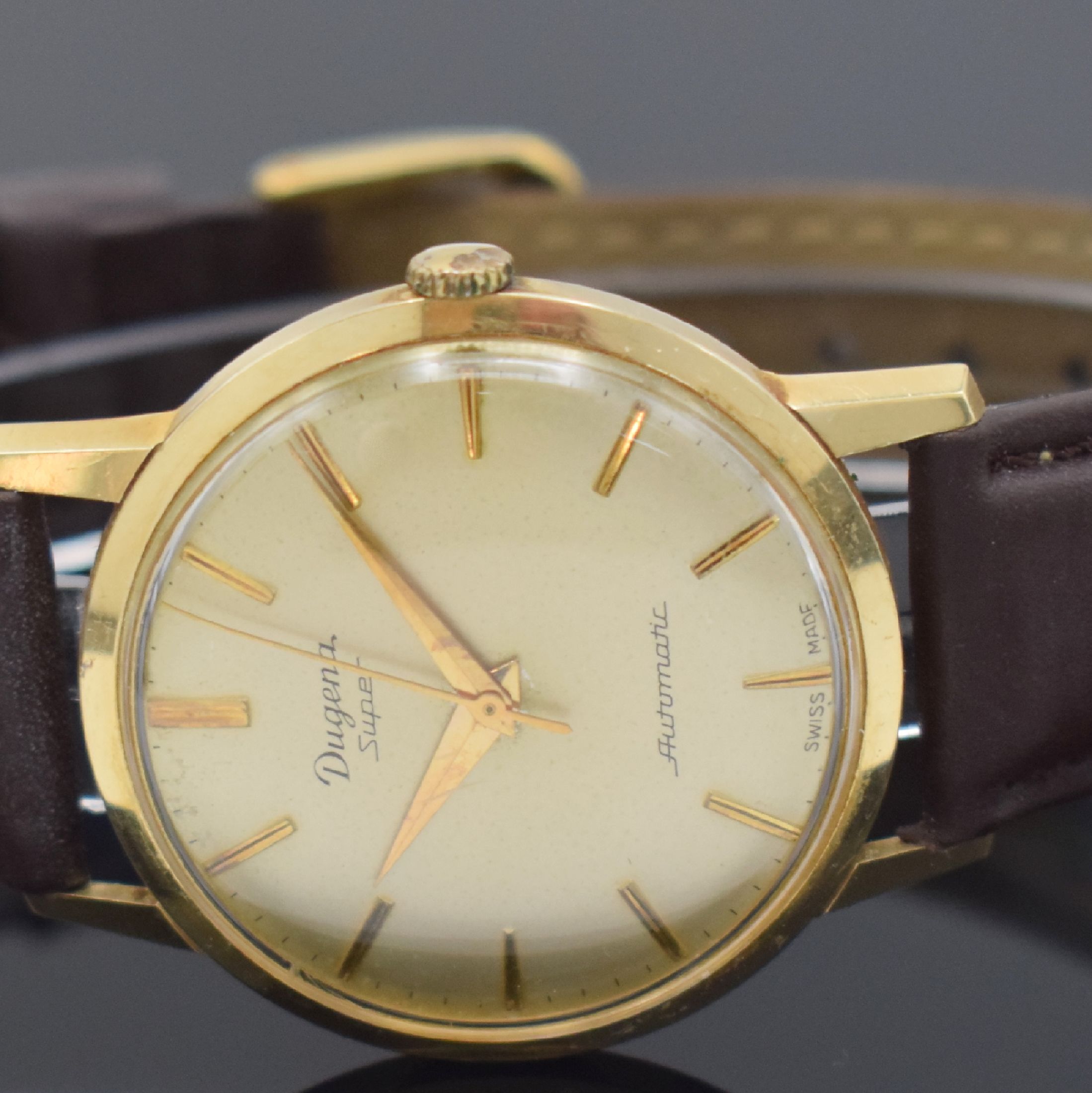 Detail b: DUGENA Herrengolduhr Modell Super in GG 585/000, Schweiz um 1960, Automatik, Geh. teils angel., Boden & Glasrand aufgedr., vers. Zifferbl. altersbed. ...