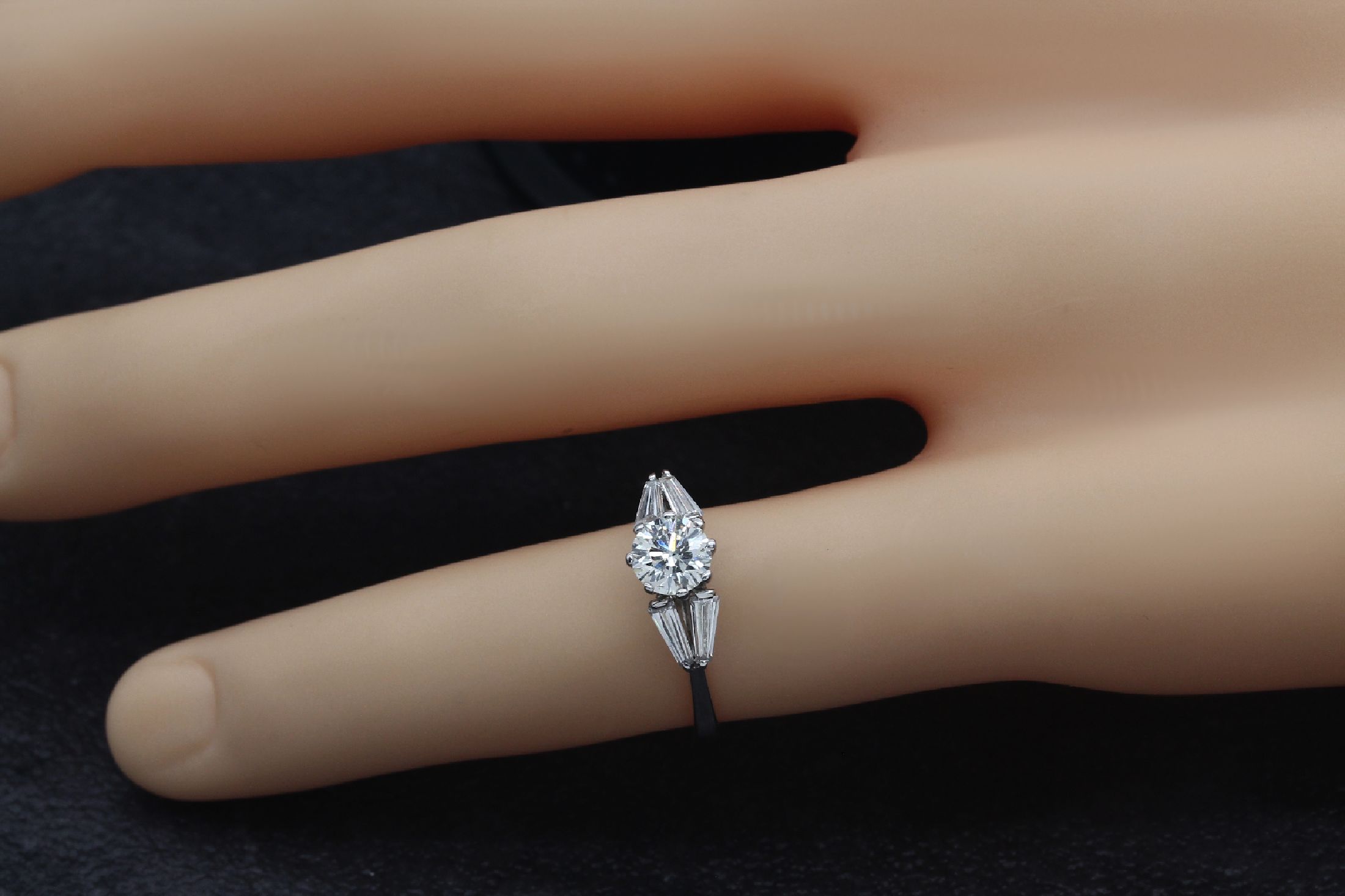 Detail b: 18 kt Gold Diamant-Ring, WG 750/000, 1 Brillant ca. 0.60 ct get. Weiß/si, 4 Diamant -Trapeze zus. ca. 0.50 ct Weiß/ vs, total ca. 1.10 ct get. ...