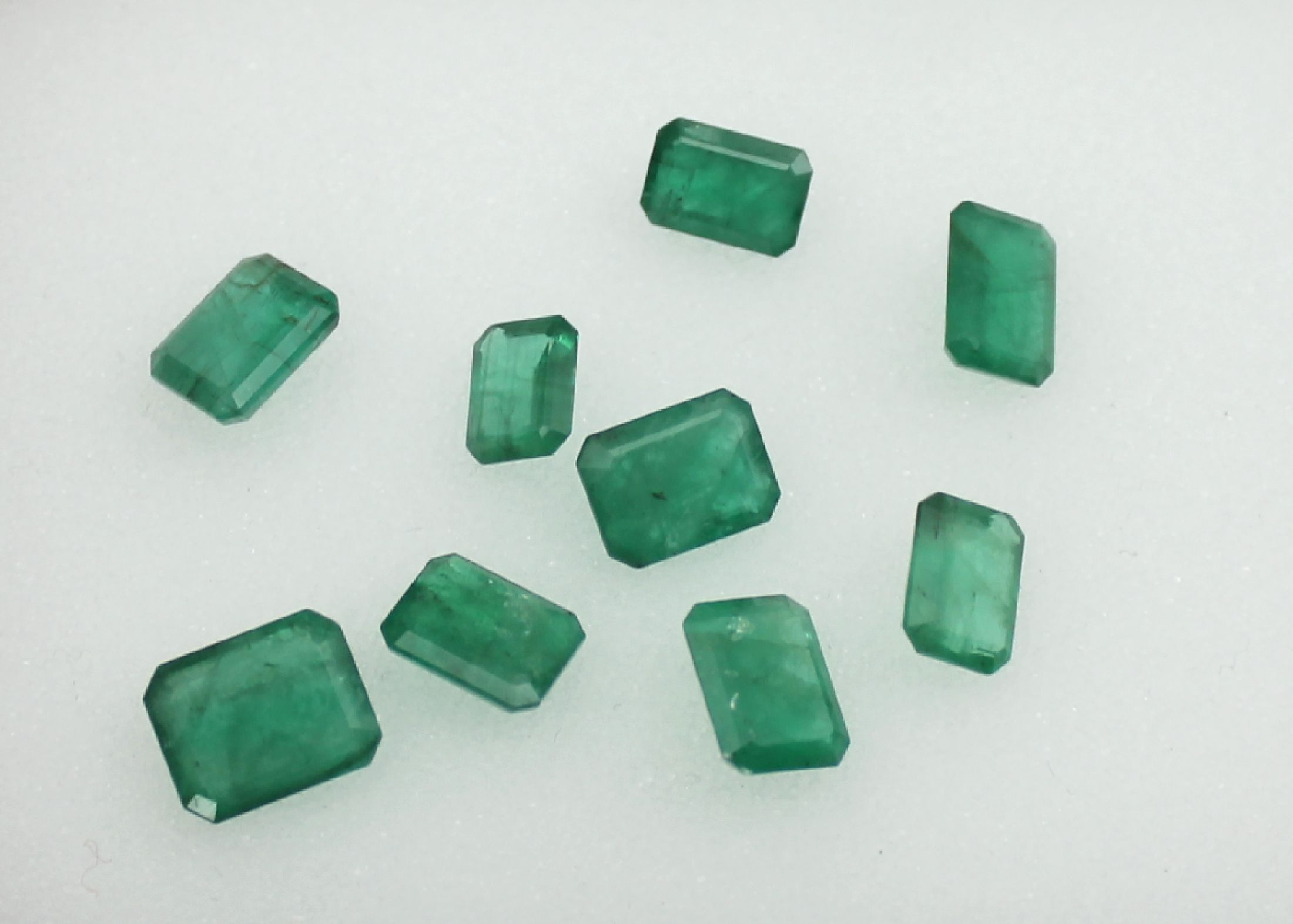 Lot 9 lose Smaragde, zus. ca. 18.01 ct, Treppenschliffe in versch. Größen und Formen, nat. Merkmale
