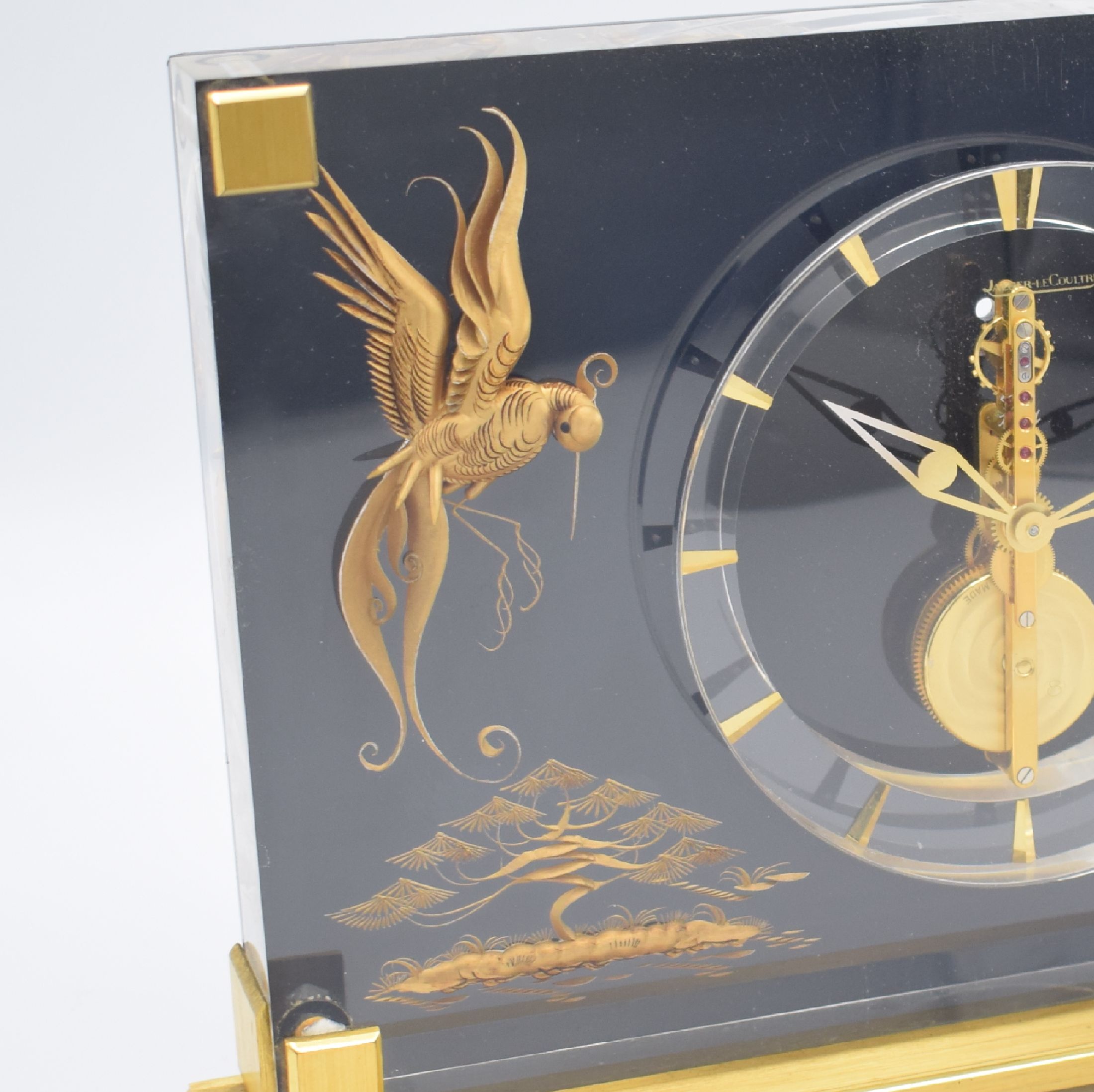 Detail b: Jaeger-LeCoultre Marina 8-Tage Tischuhr mit Stabwerk Referenz 350, Schweiz um 1960, Plexiglas-Geh. auf verg. Stand, gold. Paradiesvogel-Motiv vor ...