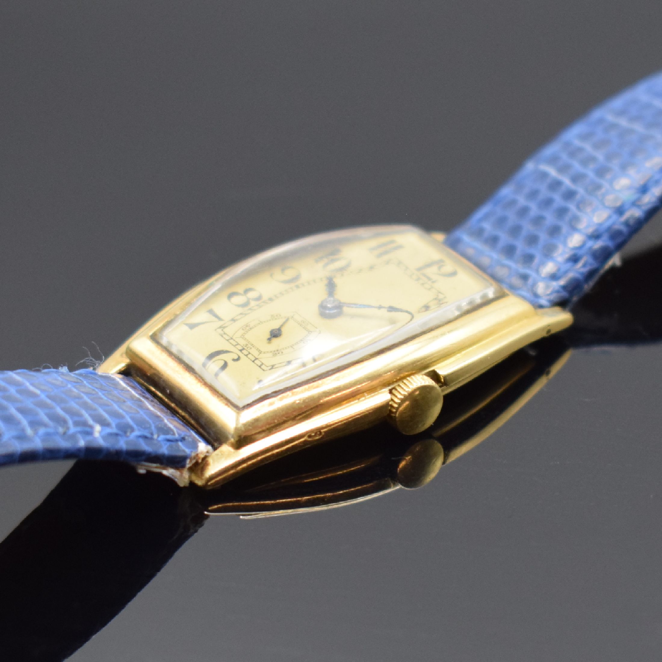 Detail b: Frühe tonneauförmige Armbanduhr in GG 750/000, Schweiz um 1925, Handaufzug, Scharniergeh., gold. Zifferbl. m. arab. Zahlen, gebl. Zeiger, Ankerwerk ...