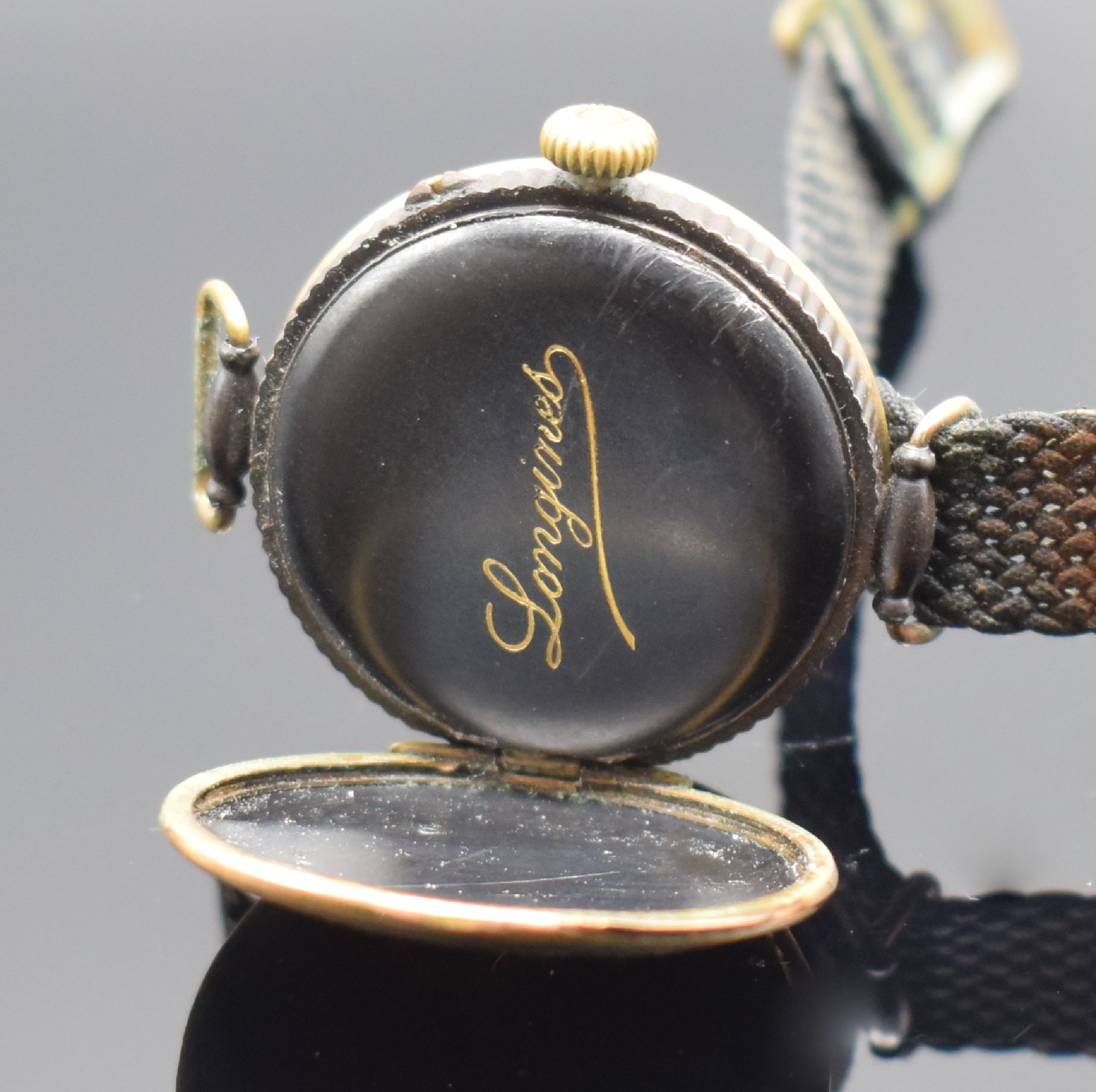 Detail c: LONGINES frühe Herrenarmbanduhr, Handaufzug, Schweiz um 1914, brüniertes Geh., Scharnierboden altersbed. oxidiert/rost., Cuv. m. Schriftzug ...
