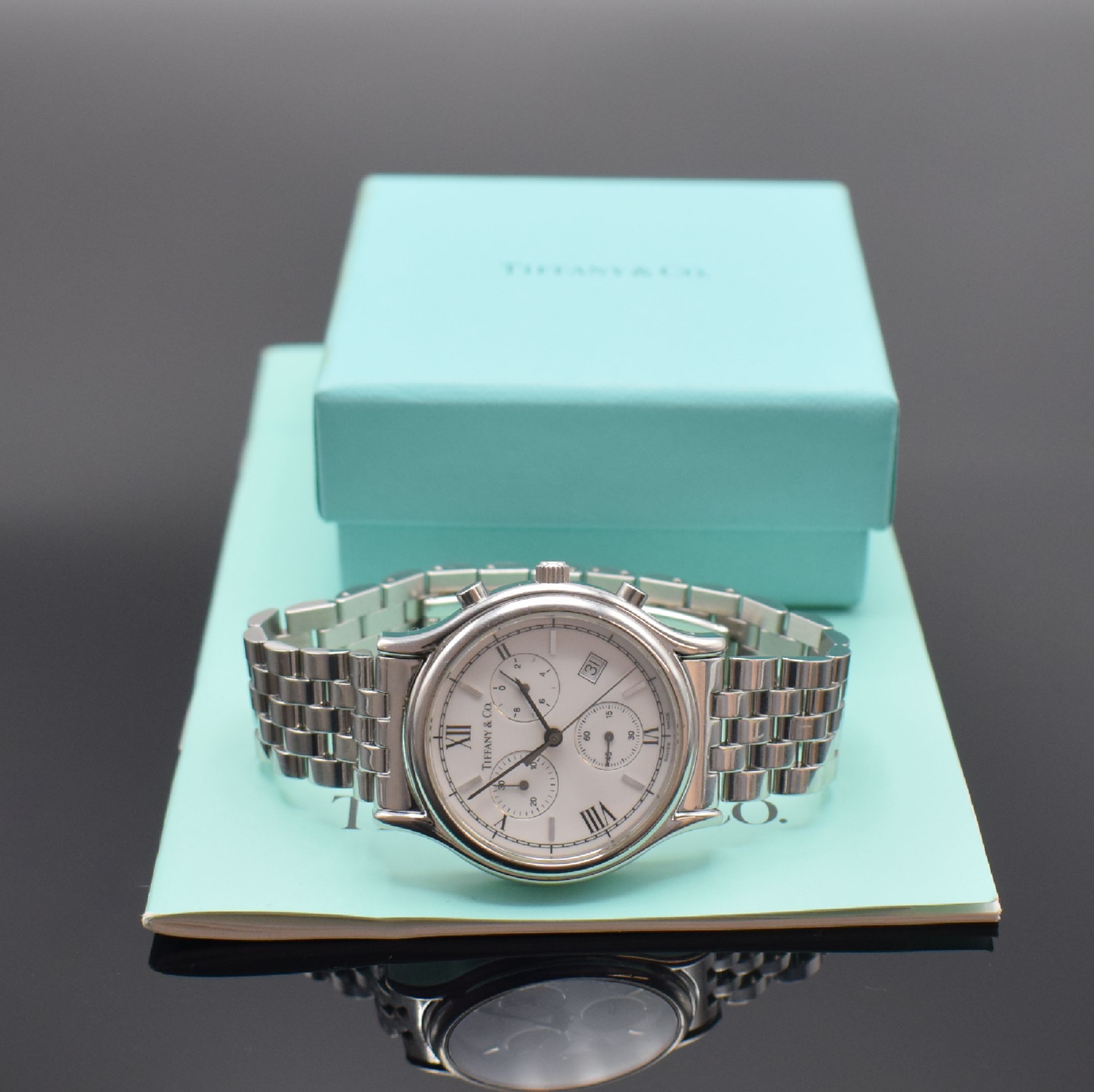 Detail e: TIFFANY & CO. Armbandchronograph, quarz, Edelstahlgeh. inkl. Gliederband m. dopp. Faltschl., Boden aufgedr., emailfarb. Zifferbl. m. röm. Std., Anz. ...