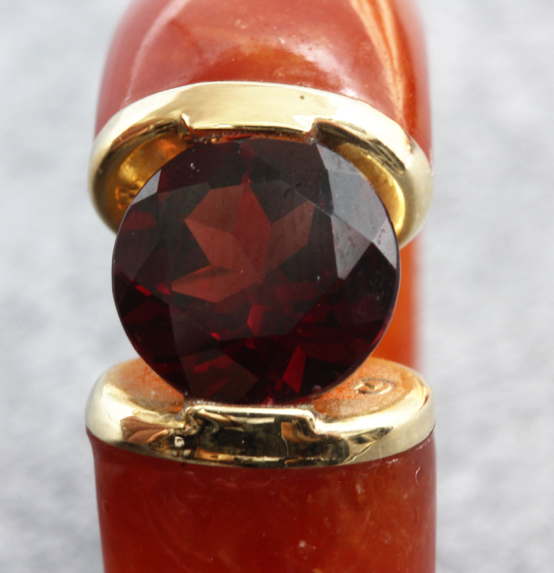 Detail a: Spannring aus orangefarb. Jade, Montierung GG 585/000, rundfacett. Granat in Ringfassung eingespannt, Meistermarke unged., RW 58