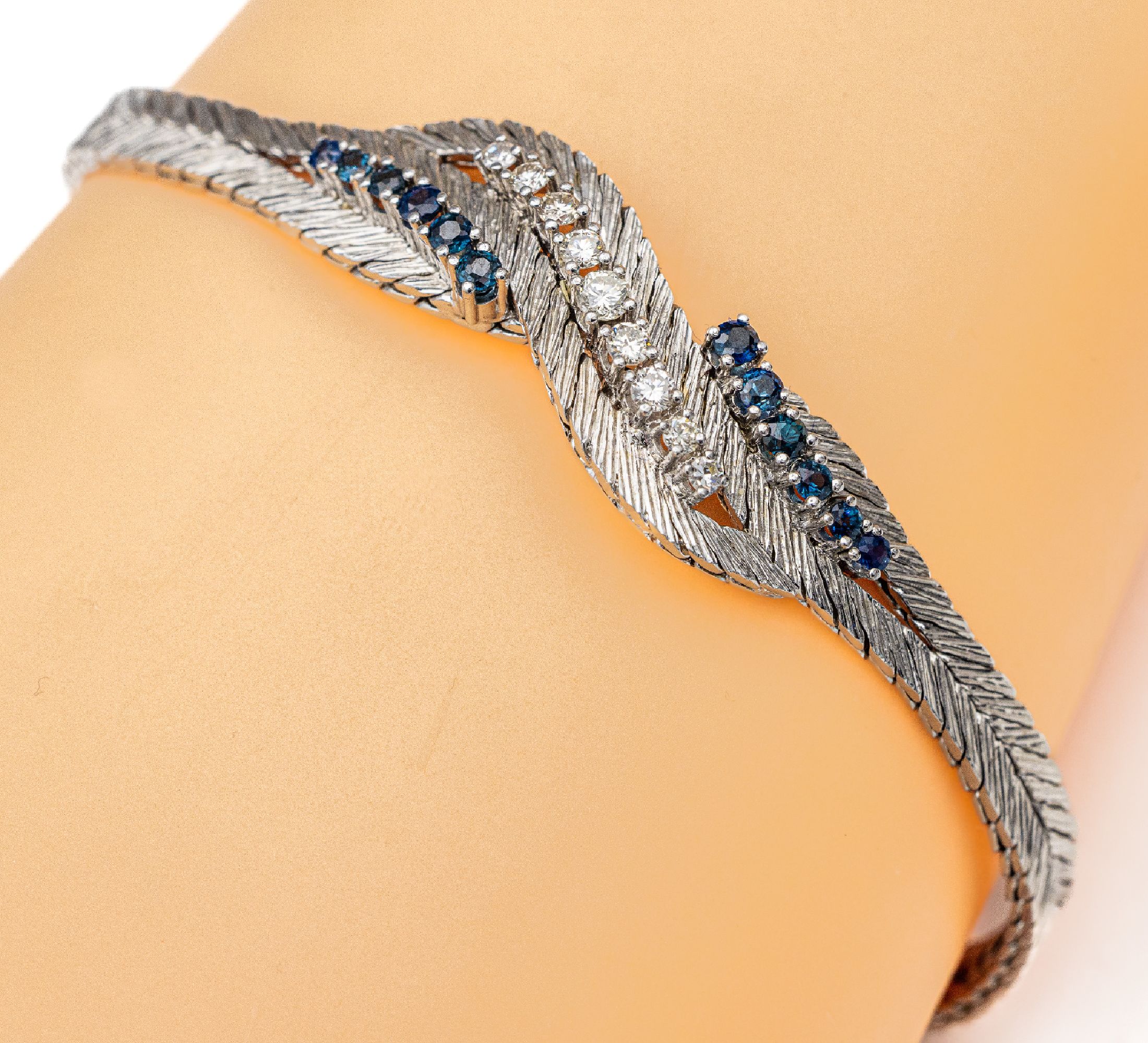 14 kt Gold Saphir-Brillant-Armband, WG 585/000 strukt., in Flechtoptik, 12 oval facett. Saphire zus. ca. 0.60 ct, mittig 9 Brillanten zus. ca. 0.45 ...