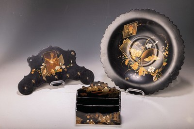 Image 26597882 - Three black lacquer objects, Japan, late Meiji period, small card stand, gold painting with courtly motifs; coat hook with fish and bird motif; Decorative plate D. 35 cm, with pigeon tail, crane and geisha motif, each with traces of age or slightly damaged
