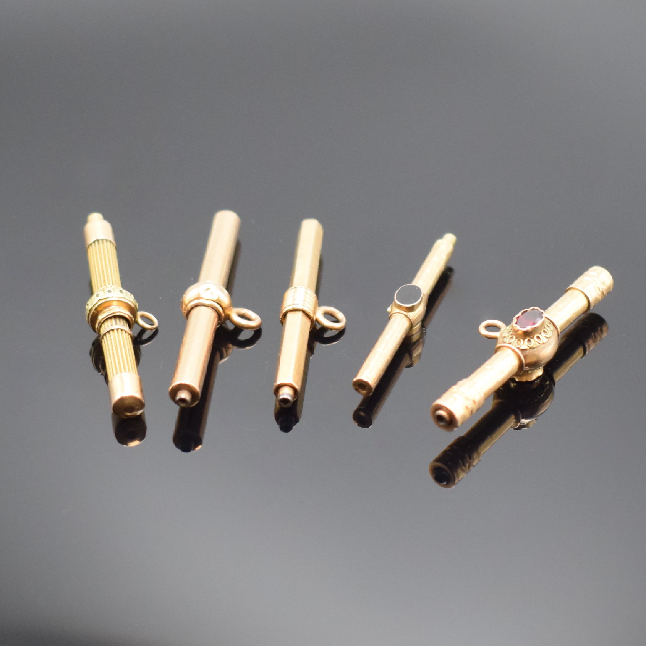 5 Taschenuhrschlüssel in RG 750/000, um 1830, Knebel-förmig, teilweise verziert, 2 mit Schmucksteinen bes., 1 x mehrfarbiges Gold, gebrauchsfähig
