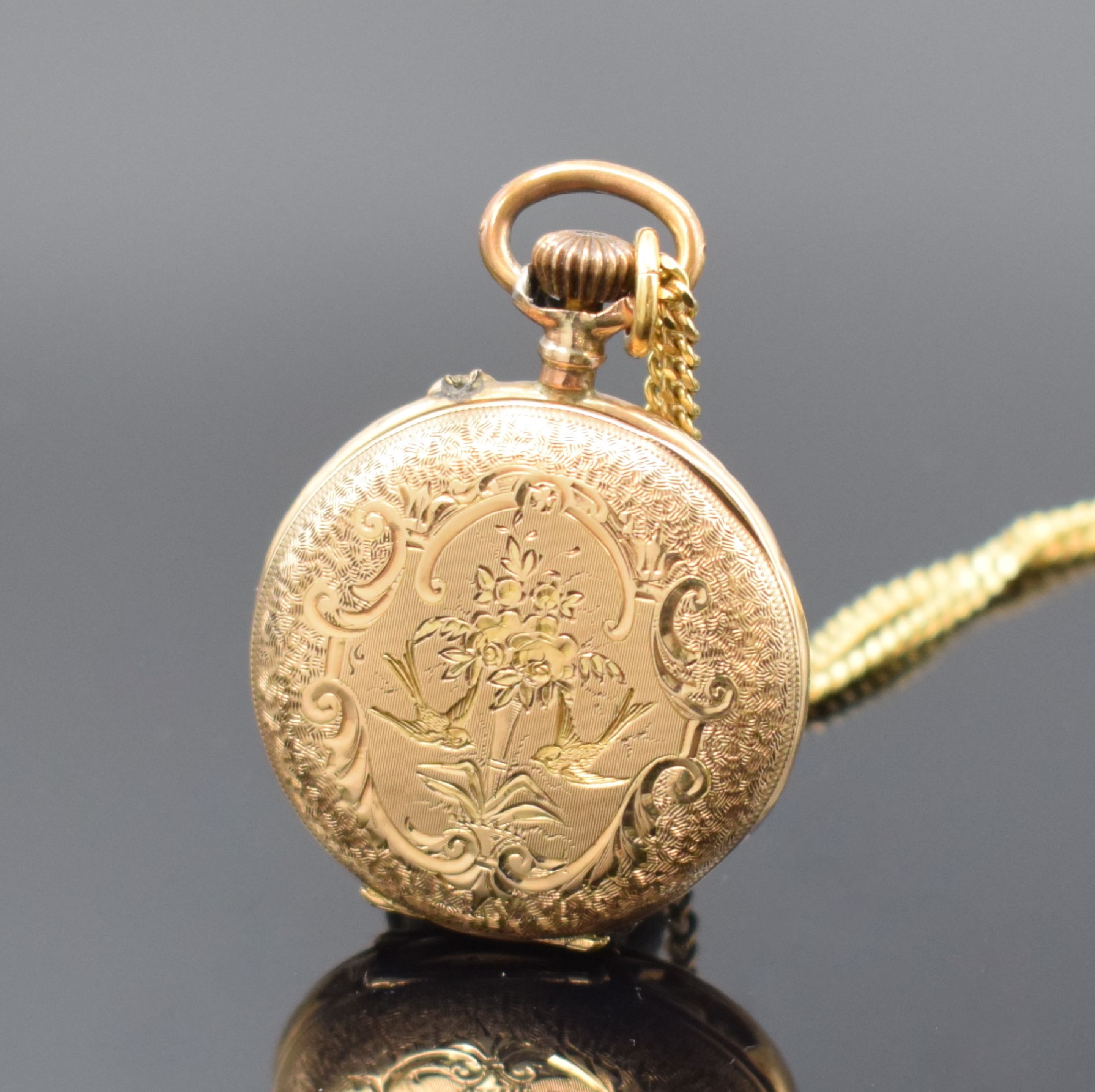 Detail a: Offene Damentaschenuhr in RG 585/000 mit Kette in GG 333/000, Schweiz um 1890, Kette sp., floral grav. Geh., Metallcuvette, Emailzifferbl. m. röm. ...