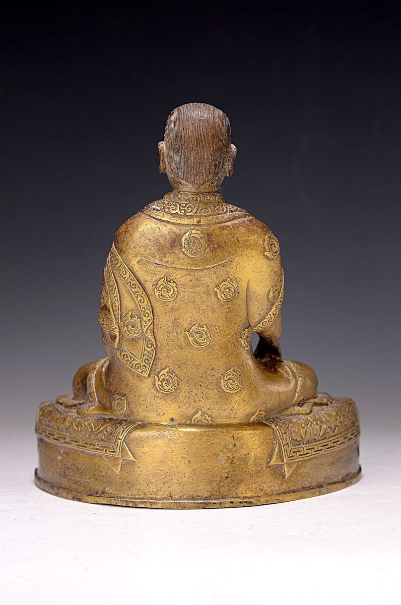 Detail a: Bronzeskulptur eines Lama, 19. Jh., Tibet, sehr schön verzierter Thron, Lotus bzw. Vajrasitz, reich verziertes Gewand, in der linken Hand das Rad ...