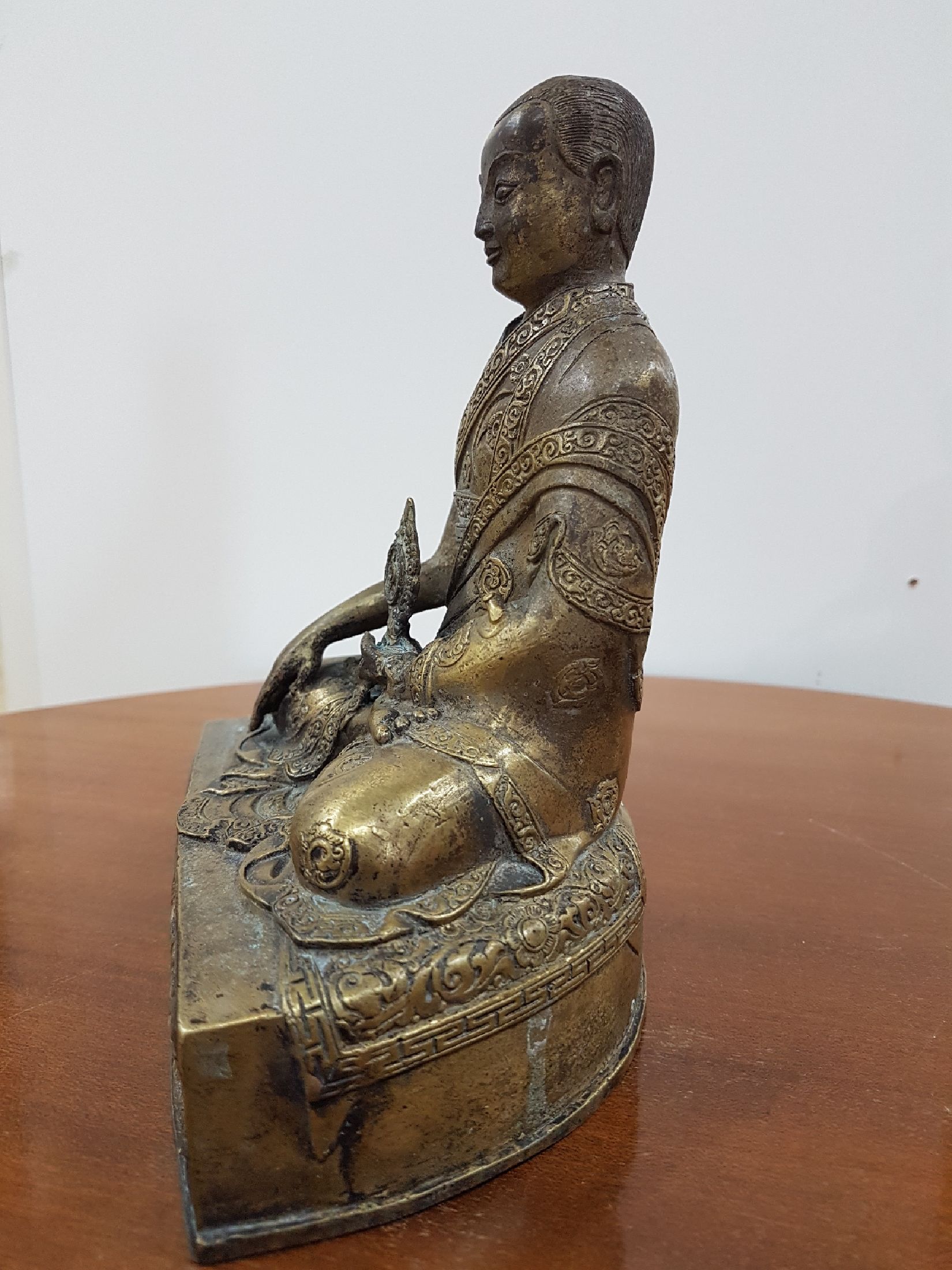 Detail c: Bronzeskulptur eines Lama, 19. Jh., Tibet, sehr schön verzierter Thron, Lotus bzw. Vajrasitz, reich verziertes Gewand, in der linken Hand das Rad ...