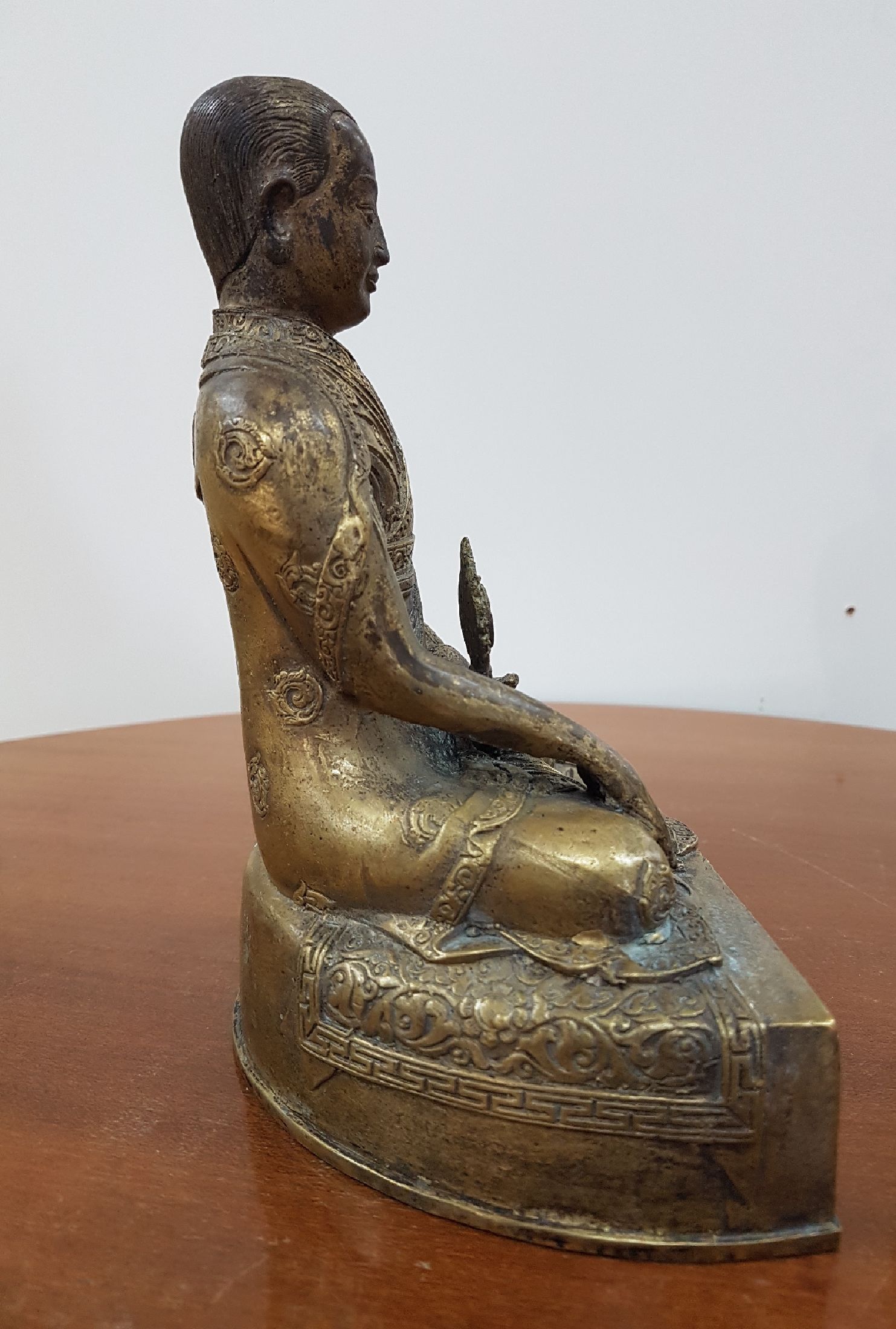 Detail e: Bronzeskulptur eines Lama, 19. Jh., Tibet, sehr schön verzierter Thron, Lotus bzw. Vajrasitz, reich verziertes Gewand, in der linken Hand das Rad ...