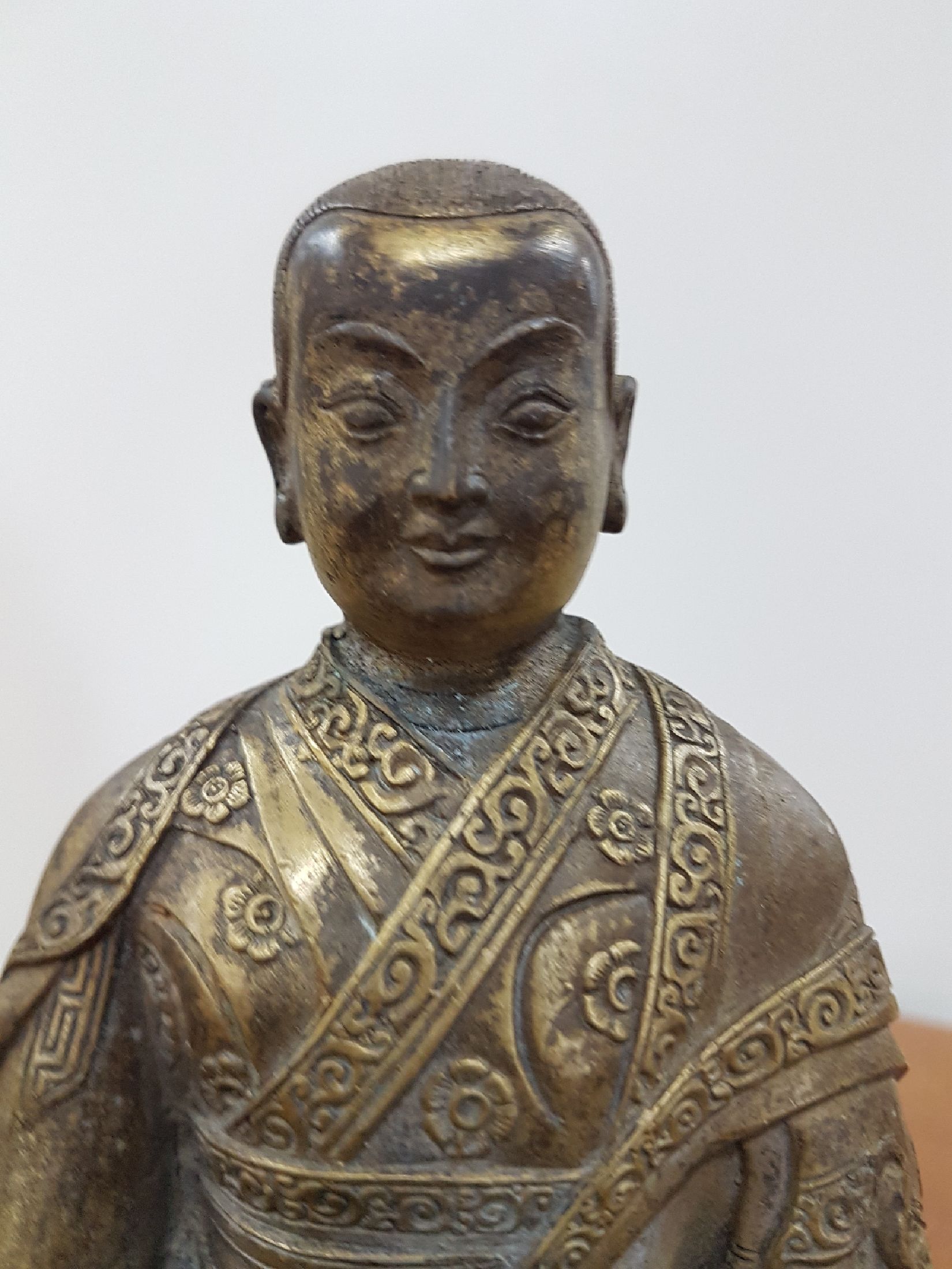 Detail g: Bronzeskulptur eines Lama, 19. Jh., Tibet, sehr schön verzierter Thron, Lotus bzw. Vajrasitz, reich verziertes Gewand, in der linken Hand das Rad ...