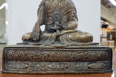 26638989h - Bronze sculpture of a lama, 19th century, Tibet, very beautifully decorated throne, lotus or vajra seat, richly decorated robe, holding the wheel of teaching in the left hand, approx. 19.5 x 16.5 x 11 cm