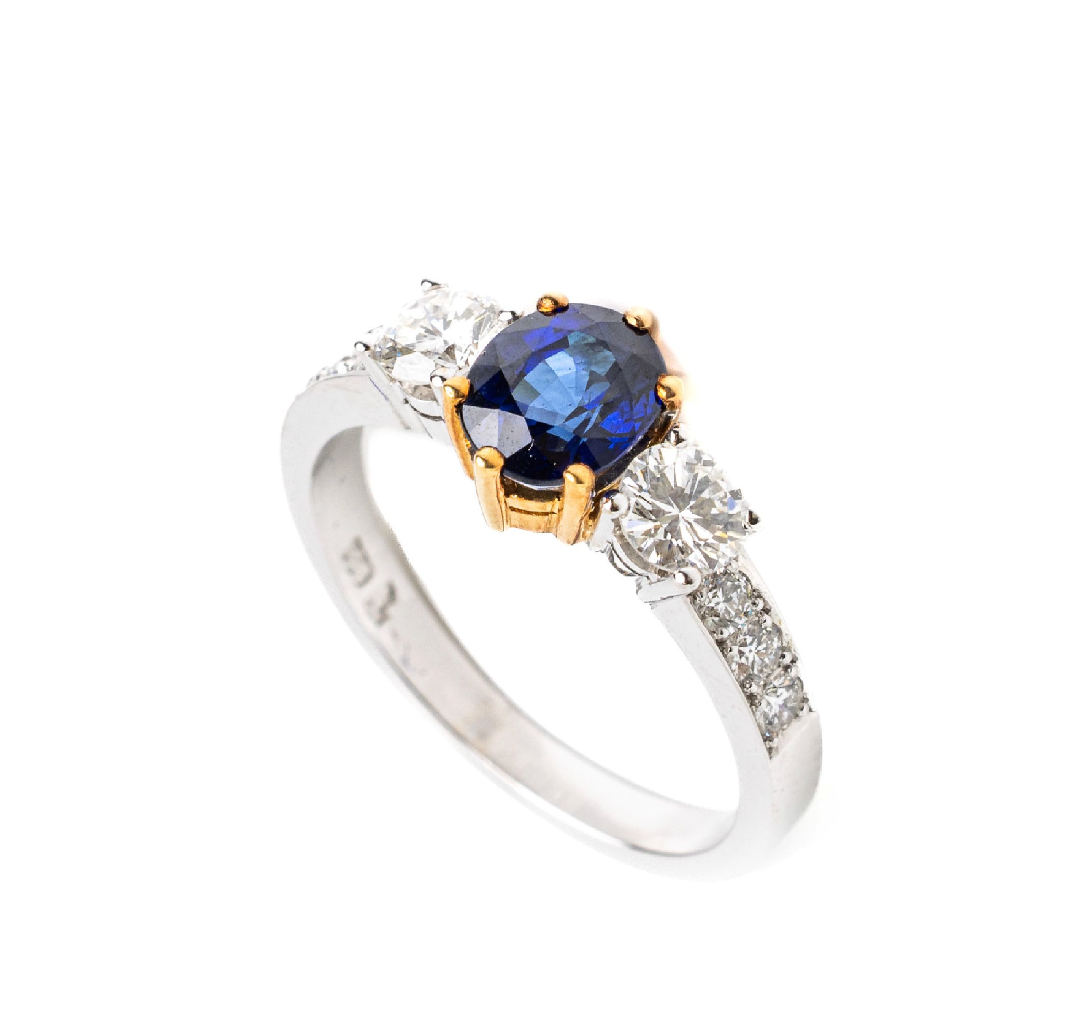 18 kt Gold Saphir Brillant Ring, WG/GG 750/000, mittig in GG gefasster ovalfacett. Saphirca. 1.31 ct, seitl. 2 Brillanten zus. ca. 0.57ct und 6 ...