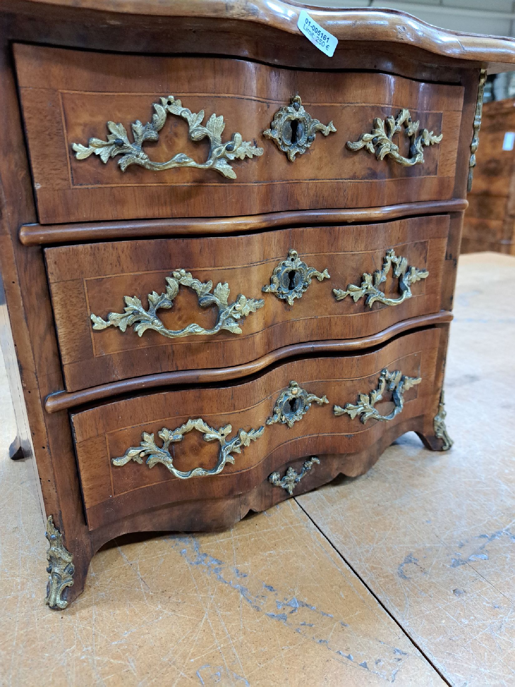Detail a: Miniaturkommode im Barockstil, 19.Jh., Nußbaumfurnier, 4-schübig, geschweifte Front, Bronzebeschläge, ohne Schlösser u. Schlüssel, ehemaliger ...