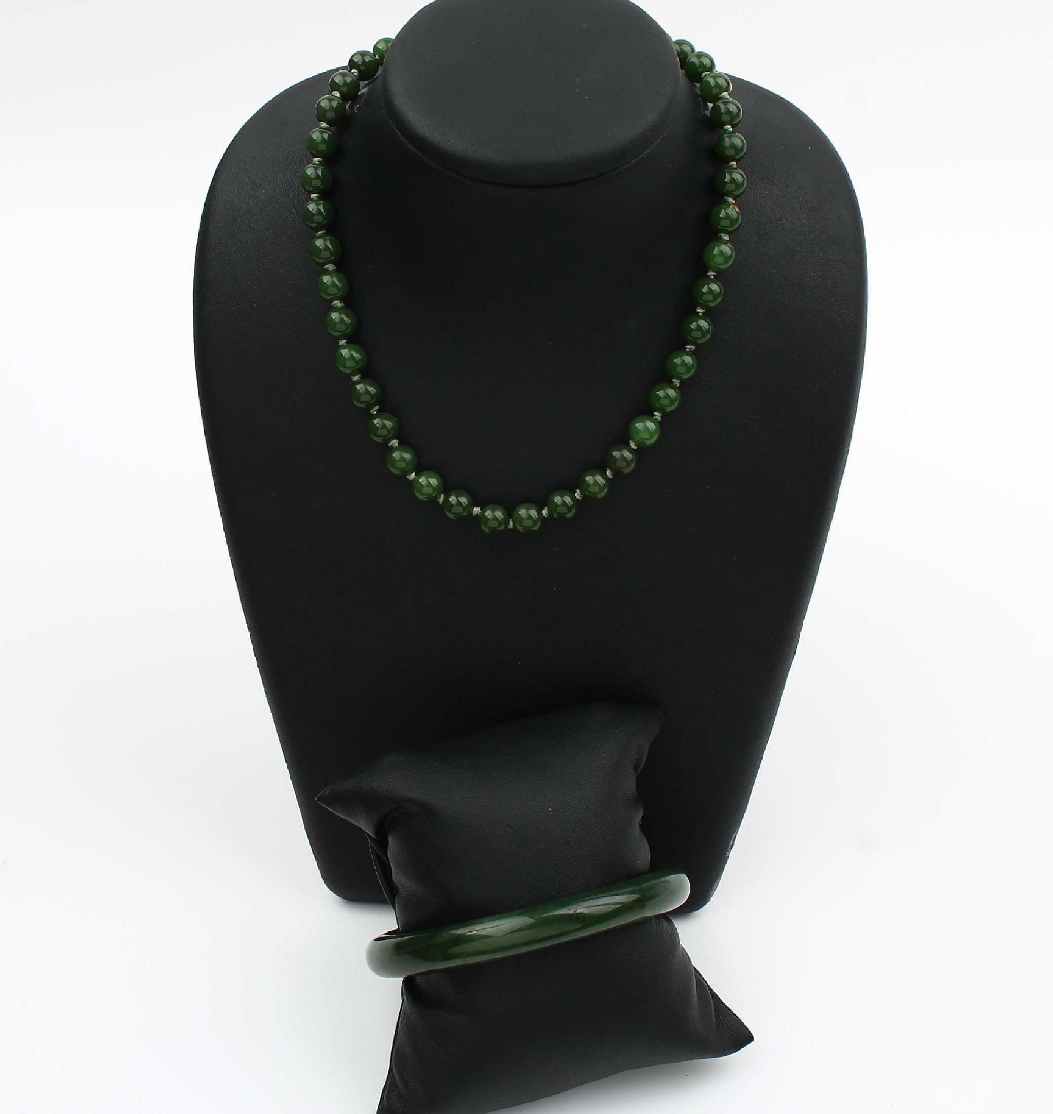 Jade-Konvolut, best. aus: 1 Armreif, D. ca.6.5 cm, und 1 Collier aus Jadekugeln, D. ca. 8.1 mm, L. ca. 93.5 cm, Federringschließe Metall verg.