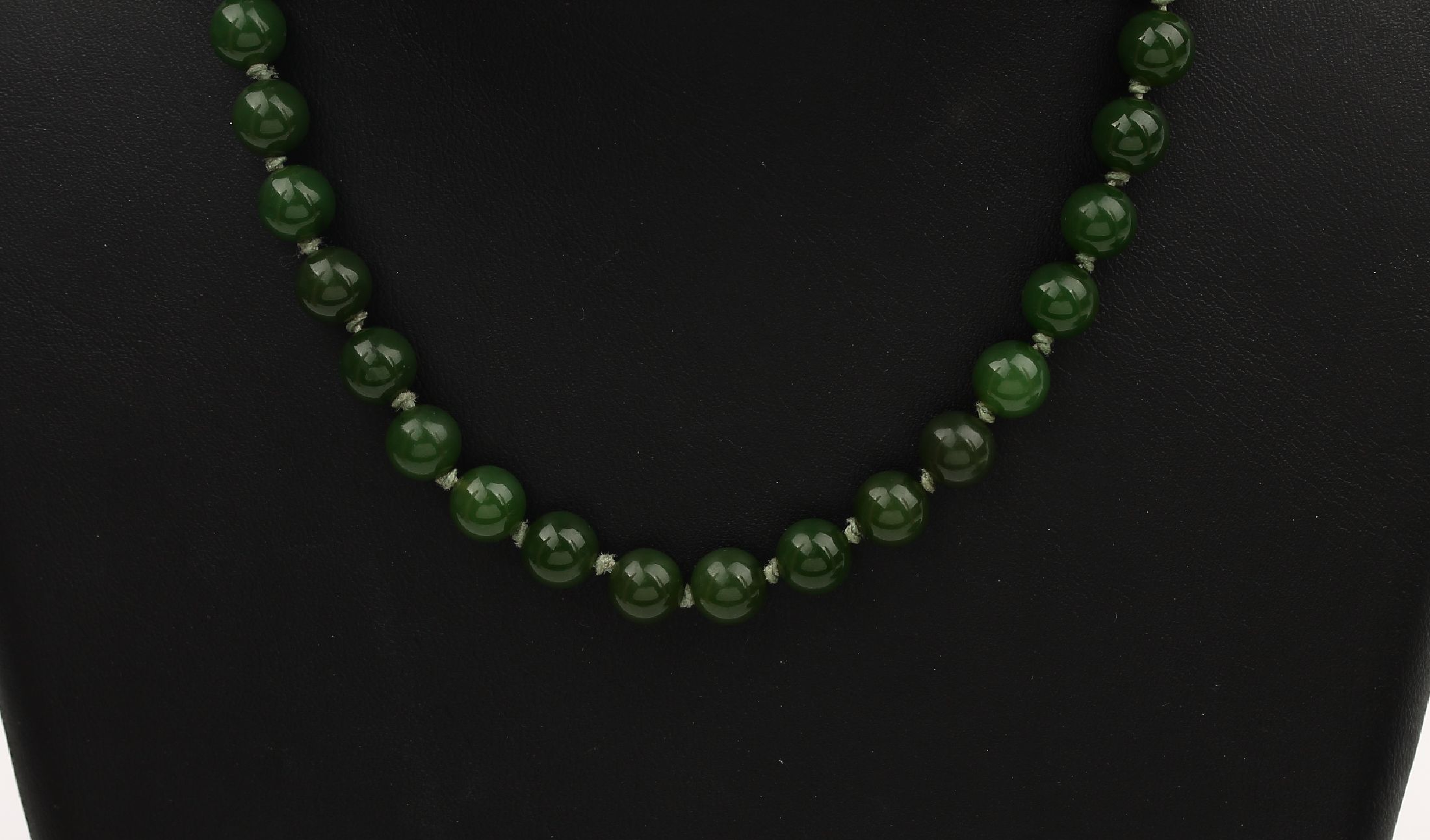 Detail a: Jade-Konvolut, best. aus: 1 Armreif, D. ca.6.5 cm, und 1 Collier aus Jadekugeln, D. ca. 8.1 mm, L. ca. 93.5 cm, Federringschließe Metall verg.
