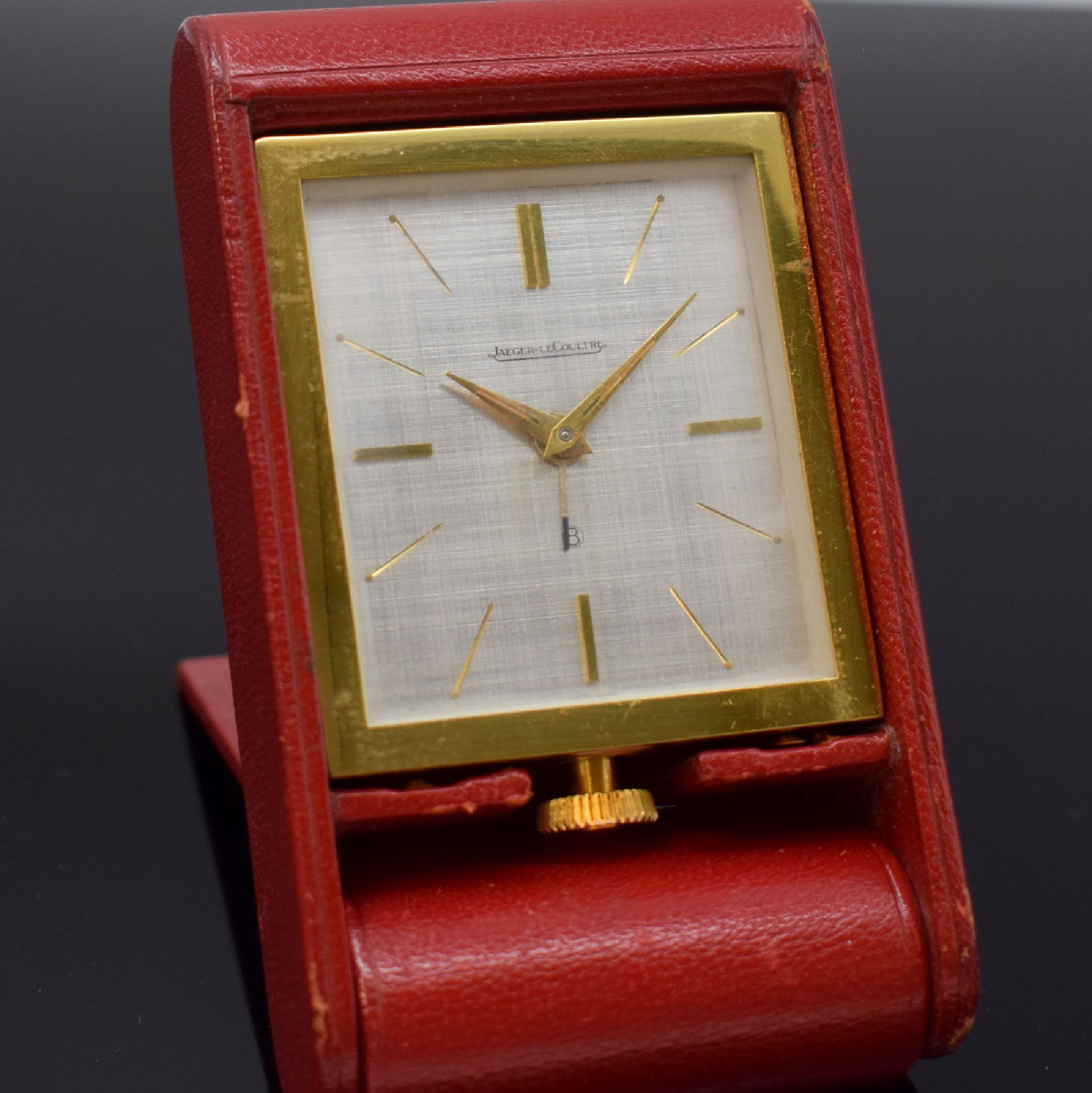 Jaeger-LeCoultre 8-Tage Reisewecker, Schweiz um 1960, aufstellbares Klappetui m. rotem Leder bezogen, verg. Geh., silb. Schraffur- Zifferbl., gold. ...