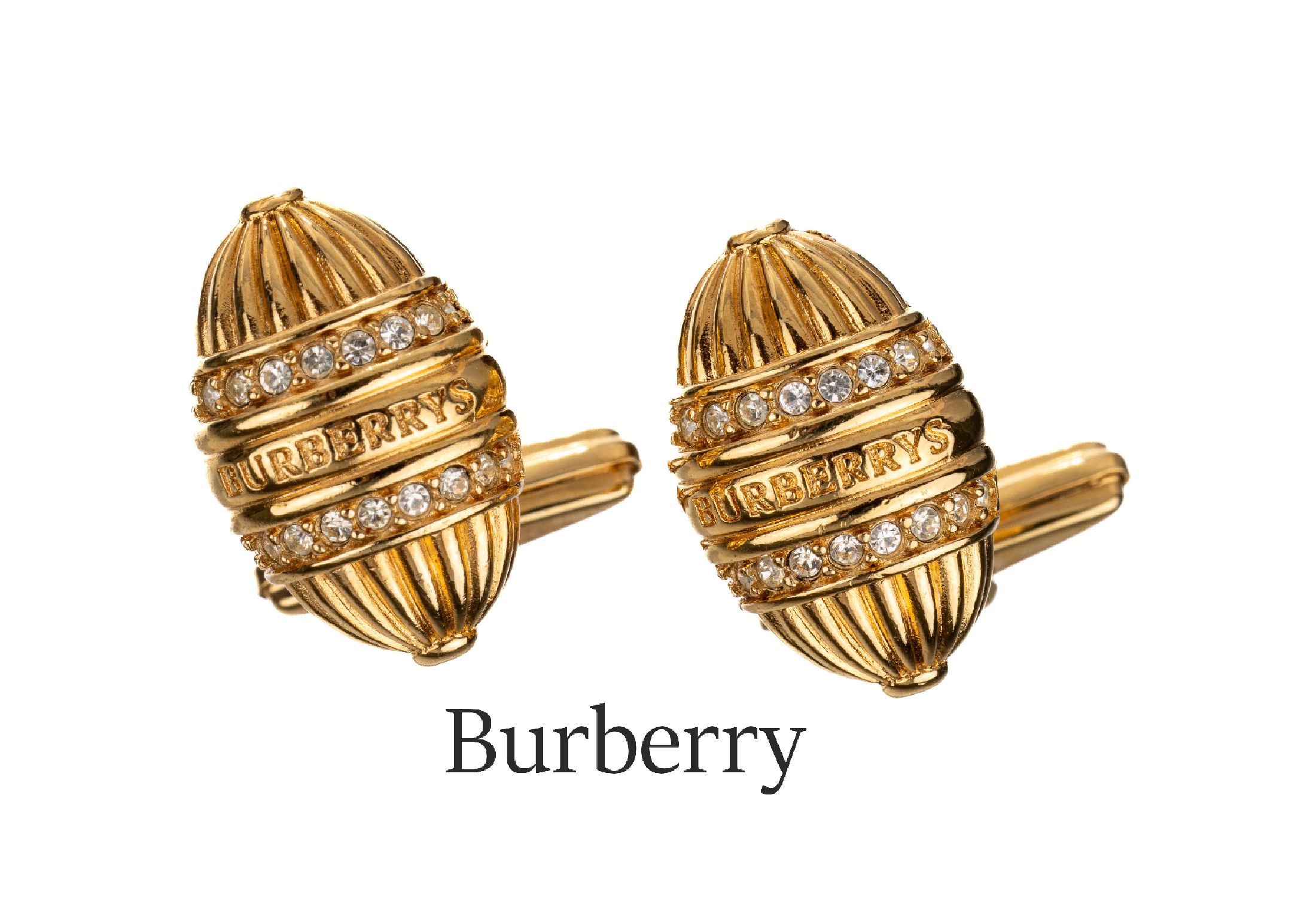 Paar BURBERRY Manschettenknöpfe, Metall verg., oval, gerieft, kl. runde Strasssteine, sign.
