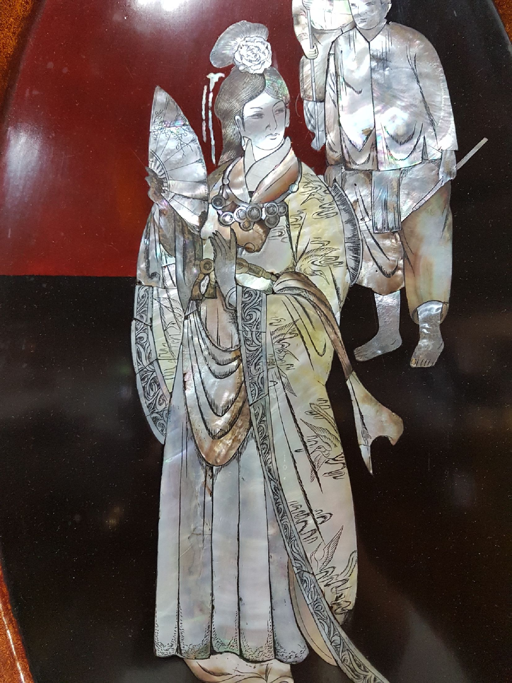 Detail d: Große Lacktablett, Japan, Mitte 20. Jh., mittig mit Perlmuttdarstellung, Geisha und zwei Personen, Fahne mit Blumen und Allegorien auf die Musik ...
