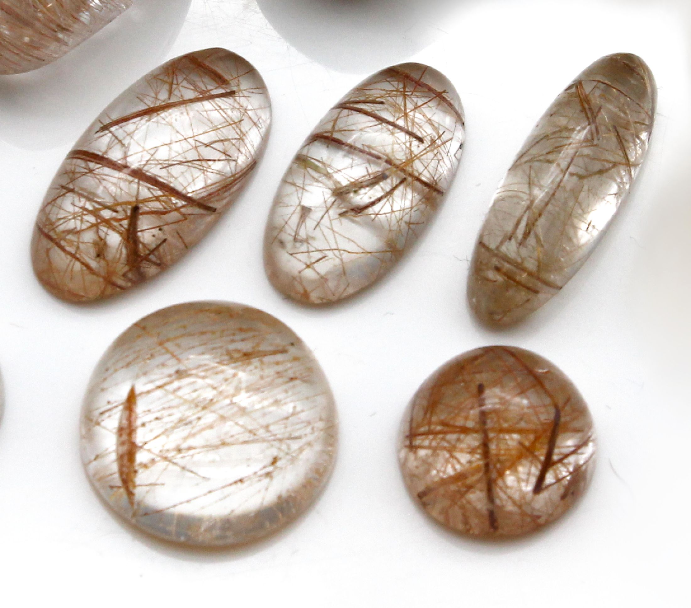 Detail b: Konvolut 16 Rutilquarz-Cabochons zus. ca. 310 ct, versch. Größen und Formen