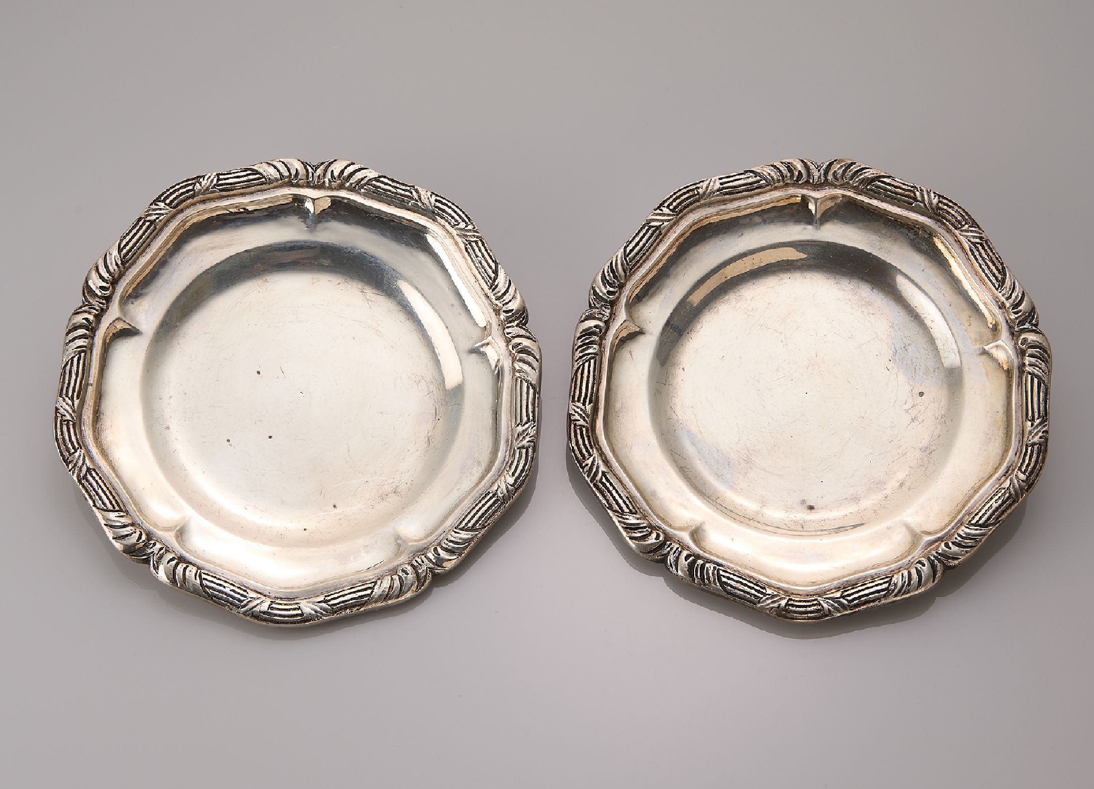 Set 2 Untersetzer, 900er Silber, wohl deutsch um 1920, geschwungener Rand mit umlaufenden Dekor, D. ca. 12 cm, ca. 244 g, Meistermarke unged.