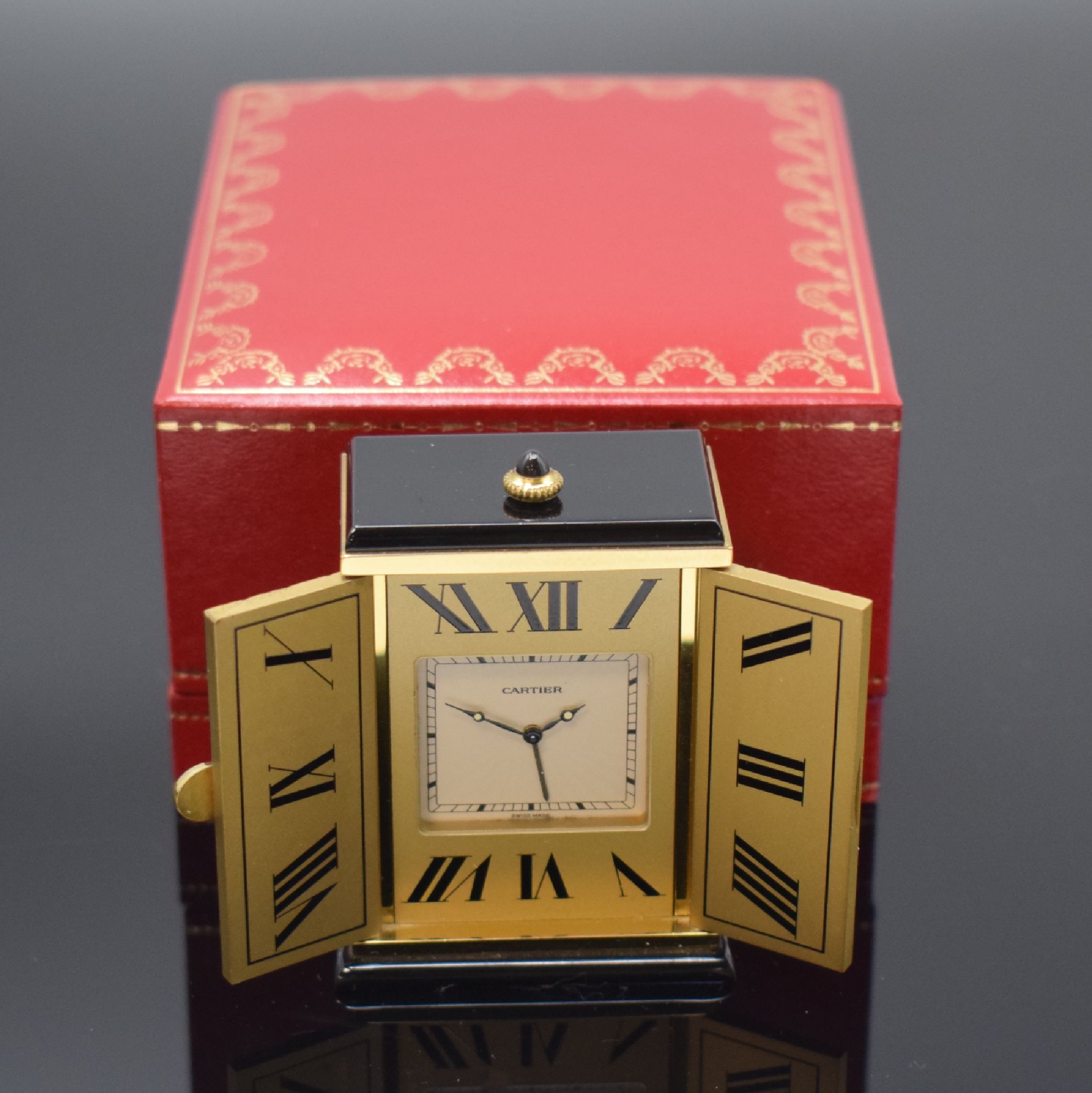 CARTIER kleiner Tischwecker, Schweiz um 1980, quarz, verg. Geh. m. Sonnendekor teils schwarz lackiert, Schmuckkrone, aufklappbar, röm. Zahlen, ...