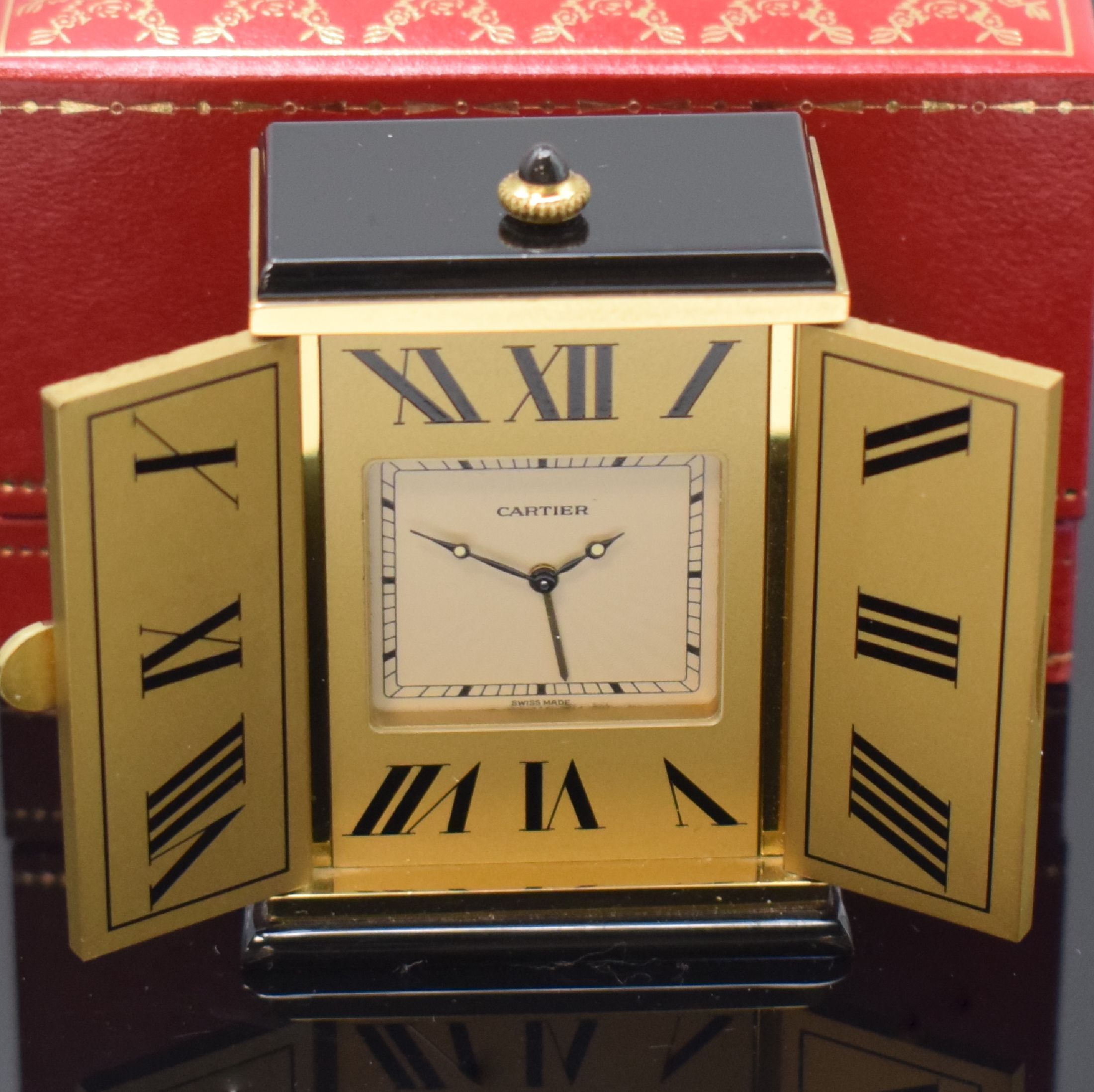 Detail a: CARTIER kleiner Tischwecker, Schweiz um 1980, quarz, verg. Geh. m. Sonnendekor teils schwarz lackiert, Schmuckkrone, aufklappbar, röm. Zahlen, ...