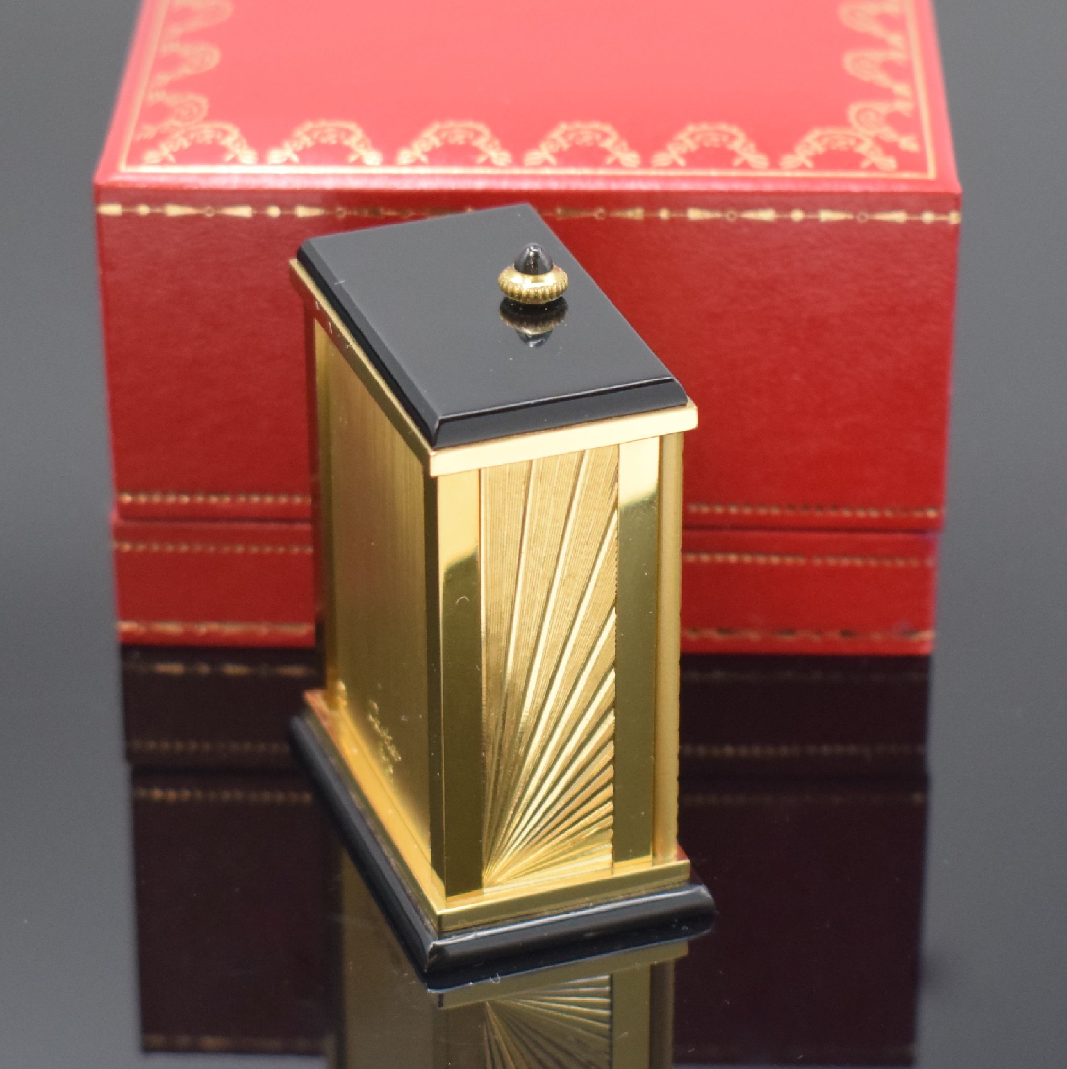 Detail c: CARTIER kleiner Tischwecker, Schweiz um 1980, quarz, verg. Geh. m. Sonnendekor teils schwarz lackiert, Schmuckkrone, aufklappbar, röm. Zahlen, ...