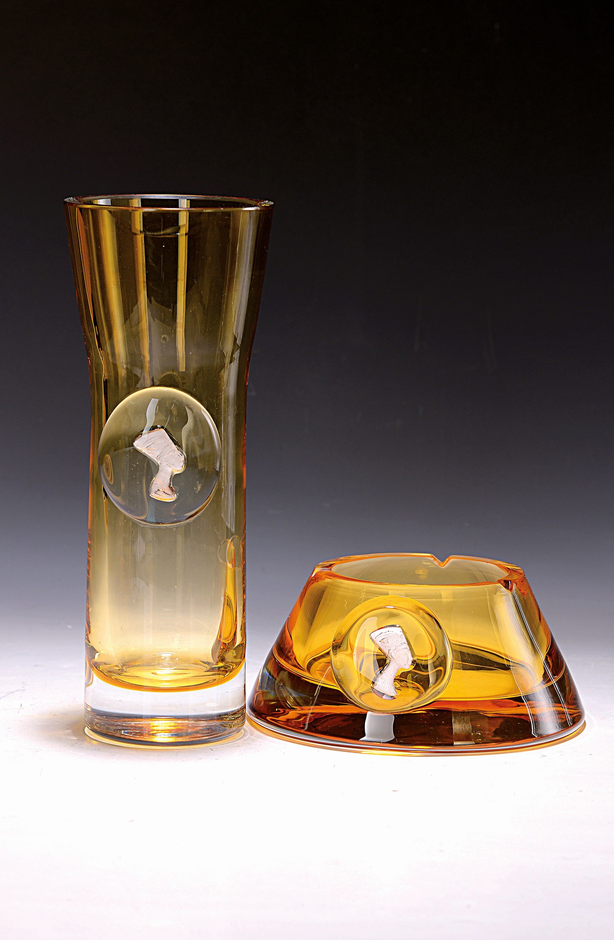 Ziervase und Aschenbecher, böhmisch, Dekor Nofretete, 20.Jh., goldgelb eingefärbtes Glas, je schauseitige Kartusche mit dem Abbild der Nofretete, ...