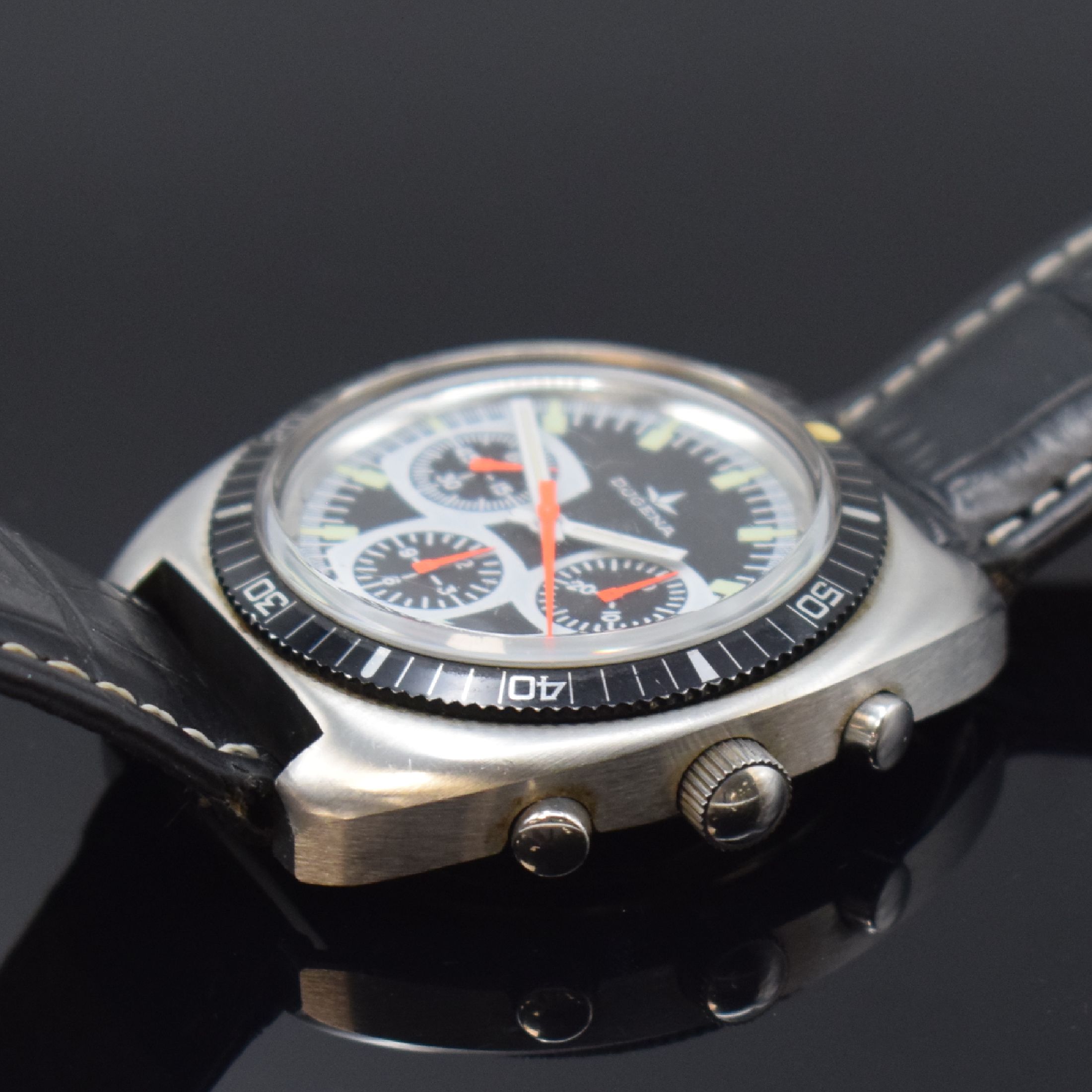 Detail b: DUGENA Armbandchronograph Referenz 157, Handaufzug, Schweiz um 1970, Edelstahlgeh., Boden verschr., Lünette m. 60er Teilung beids. drehb., schwarzes ...