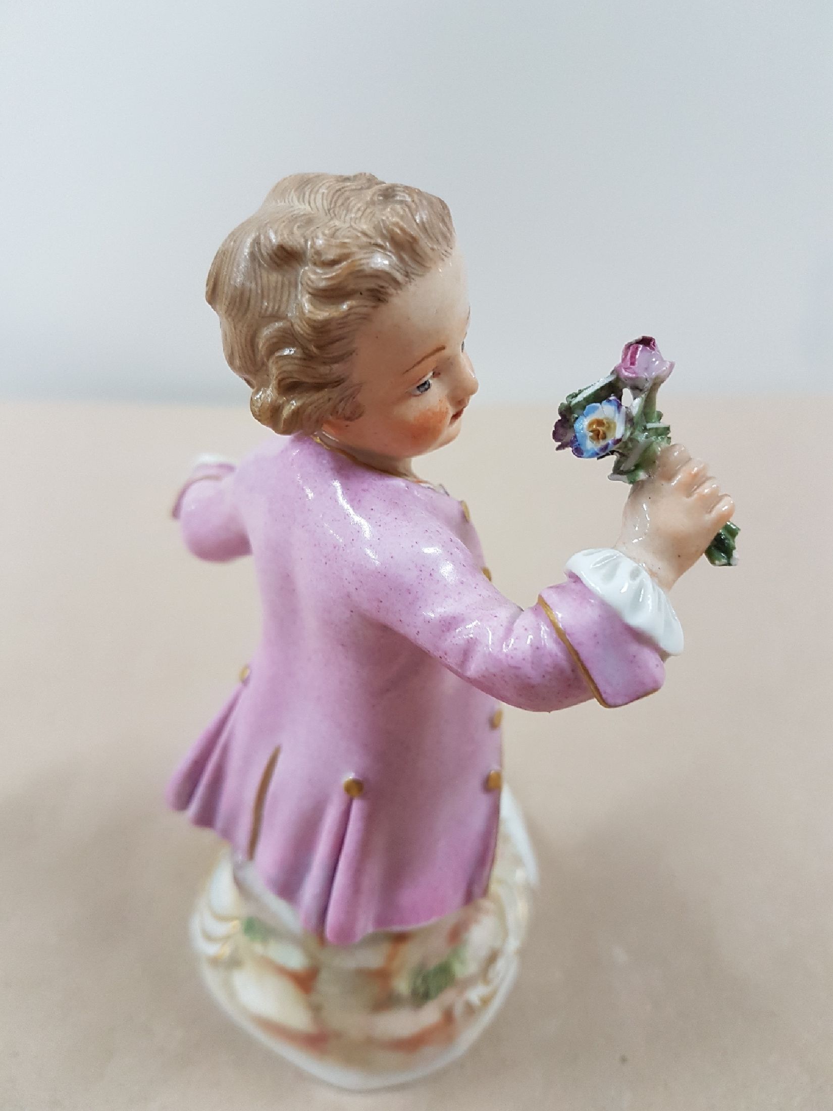 Detail b: Porzellanfigur, Meissen, um 1900, sitzender Knabe mit Rosenstrauß, polychrome Bemalung, Goldstaffage, an den Blüten und Blättern best., H. ca. 12 ...