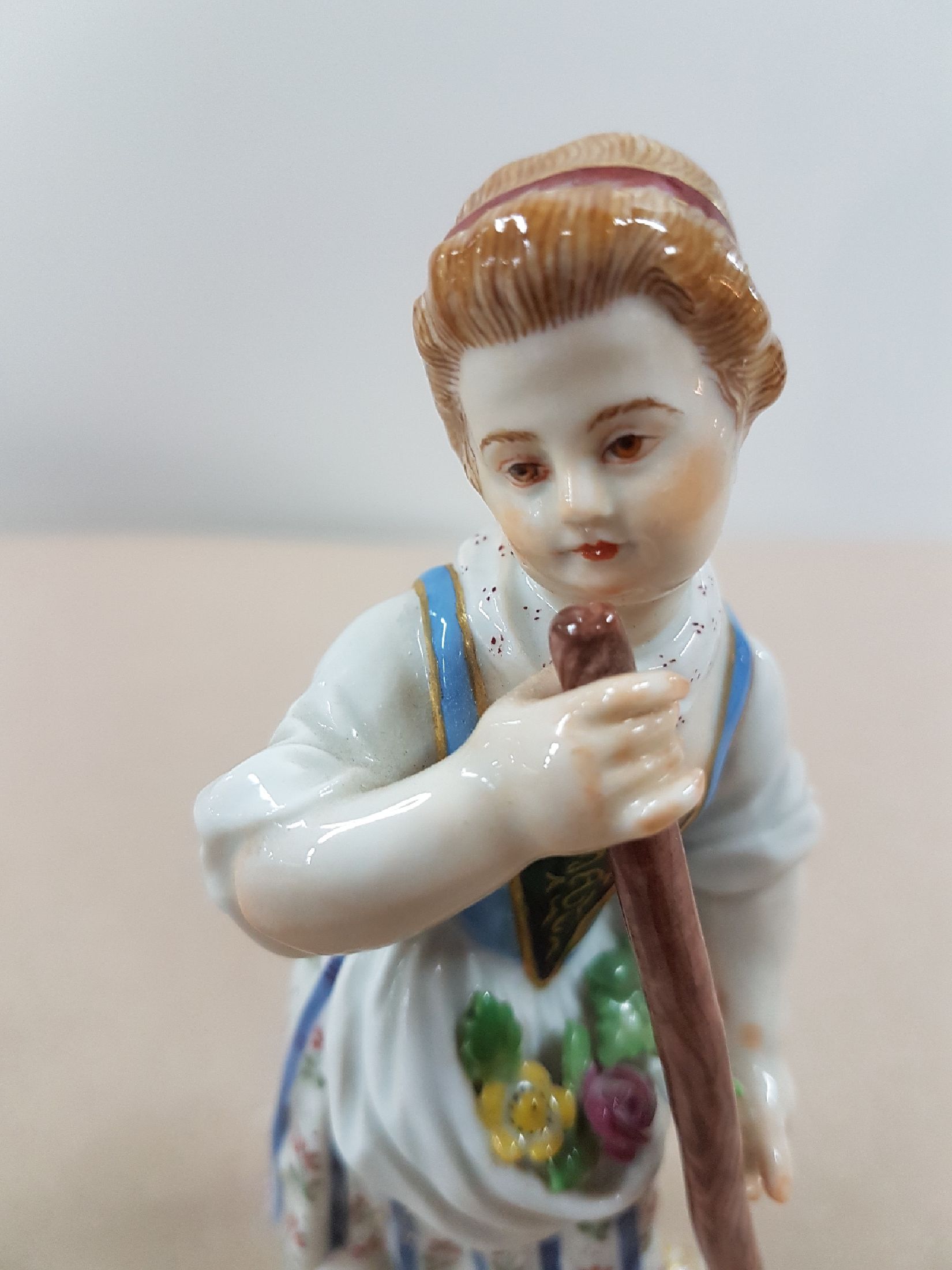 Detail e: Porzellanfigur, Meissen, 20. Jh., Gärtnerin mit Rechen, Modellnr. 60353, bunt bemalt, Goldstaffage, ca. 13 cm