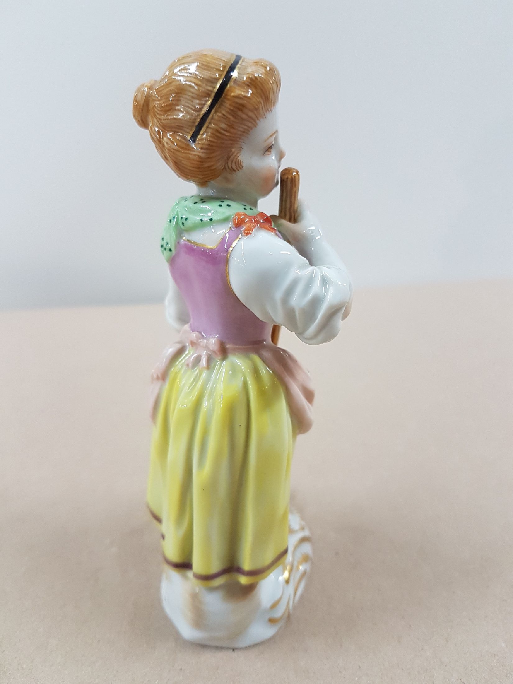 Detail b: Porzellanfigur, Meissen, wohl 60er Jahre, Gärtnerin mit Rechen, polychrom bemalt, Goldstaffage, H. 12.5 cm