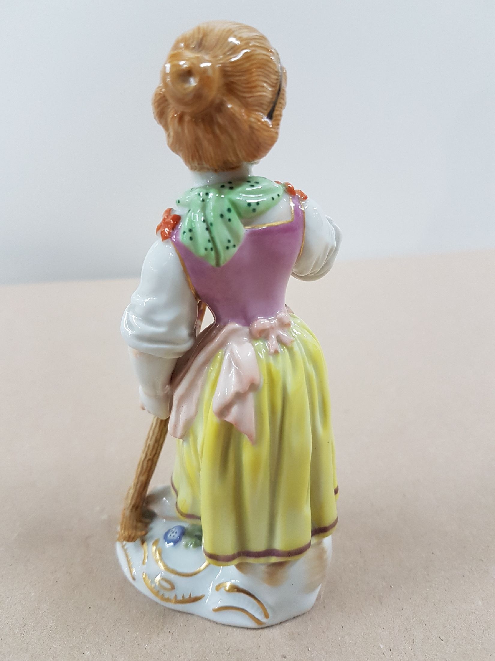 Detail c: Porzellanfigur, Meissen, wohl 60er Jahre, Gärtnerin mit Rechen, polychrom bemalt, Goldstaffage, H. 12.5 cm