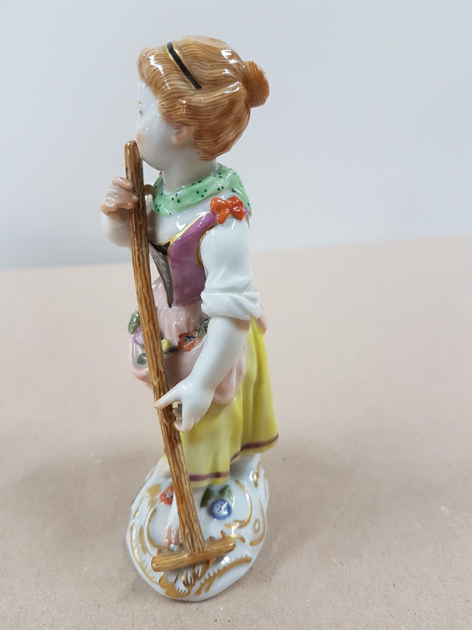 Detail d: Porzellanfigur, Meissen, wohl 60er Jahre, Gärtnerin mit Rechen, polychrom bemalt, Goldstaffage, H. 12.5 cm