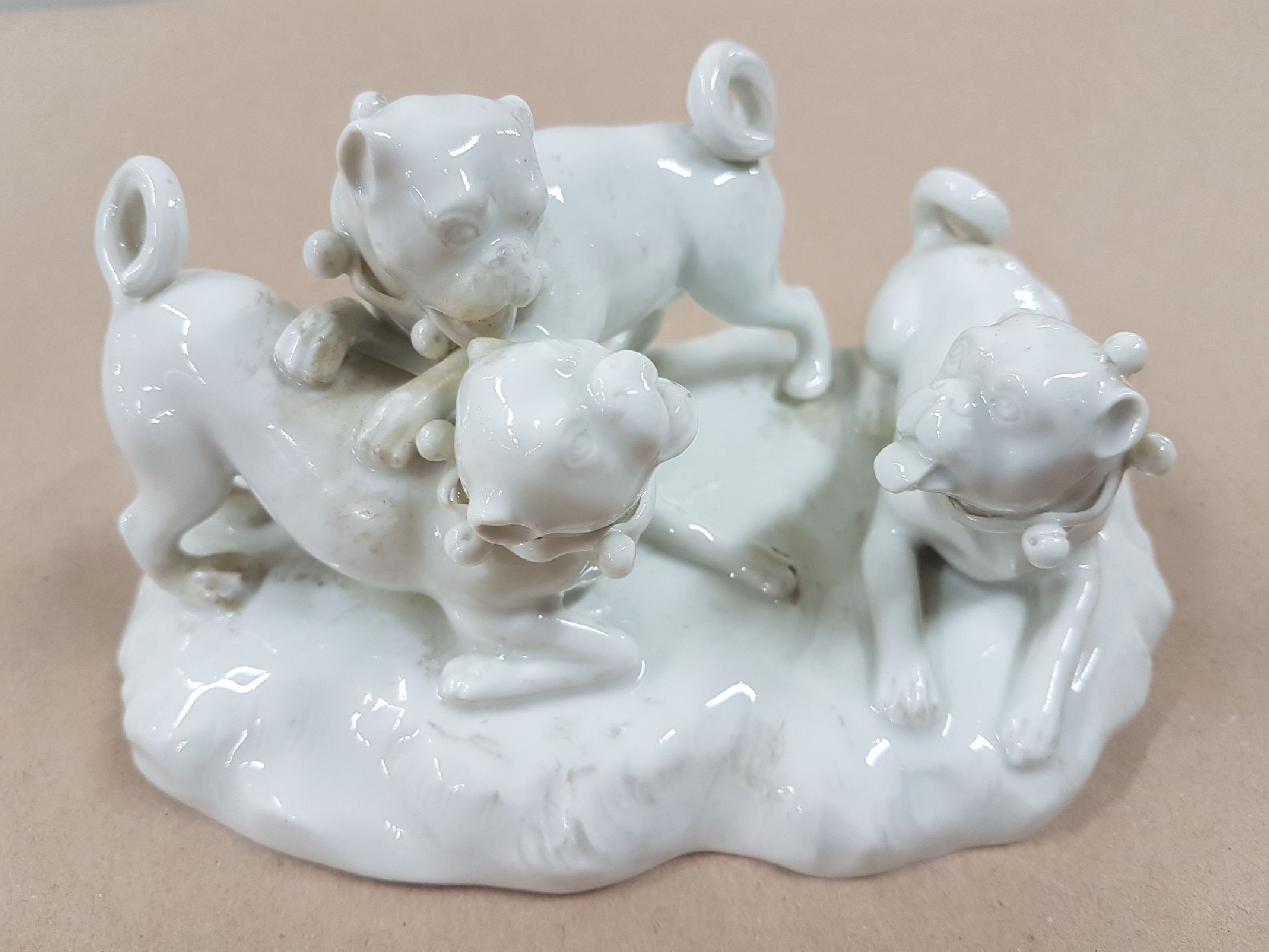 Detail a: Porzellangruppe, Meissen, 20. Jh., weiß, drei spielende Möpse, Entwurf August Ringler, Modellnr. 78836, zwei Schleifstriche,8.5 x 16 x 10 cm, ...