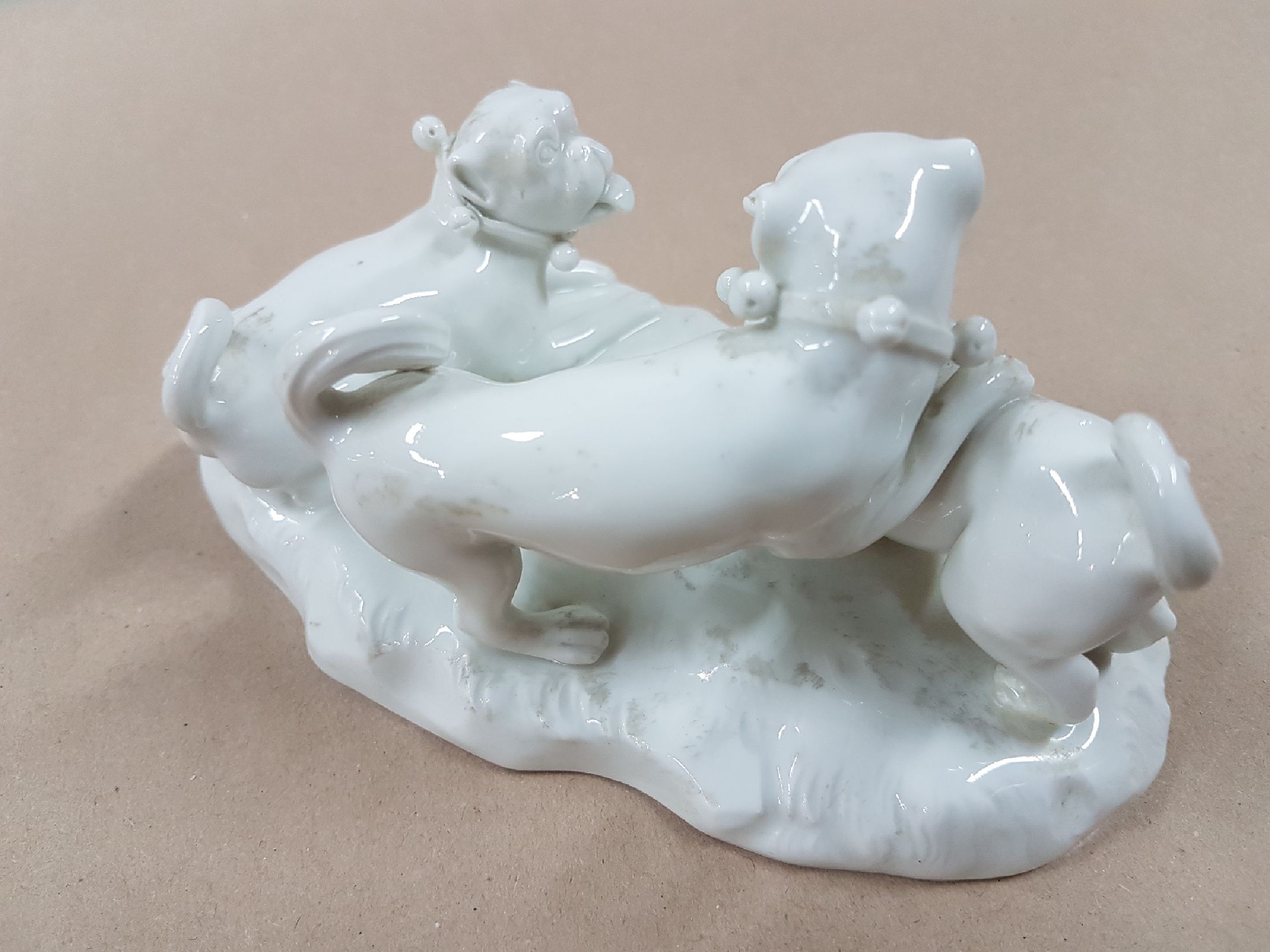 Detail b: Porzellangruppe, Meissen, 20. Jh., weiß, drei spielende Möpse, Entwurf August Ringler, Modellnr. 78836, zwei Schleifstriche,8.5 x 16 x 10 cm, ...
