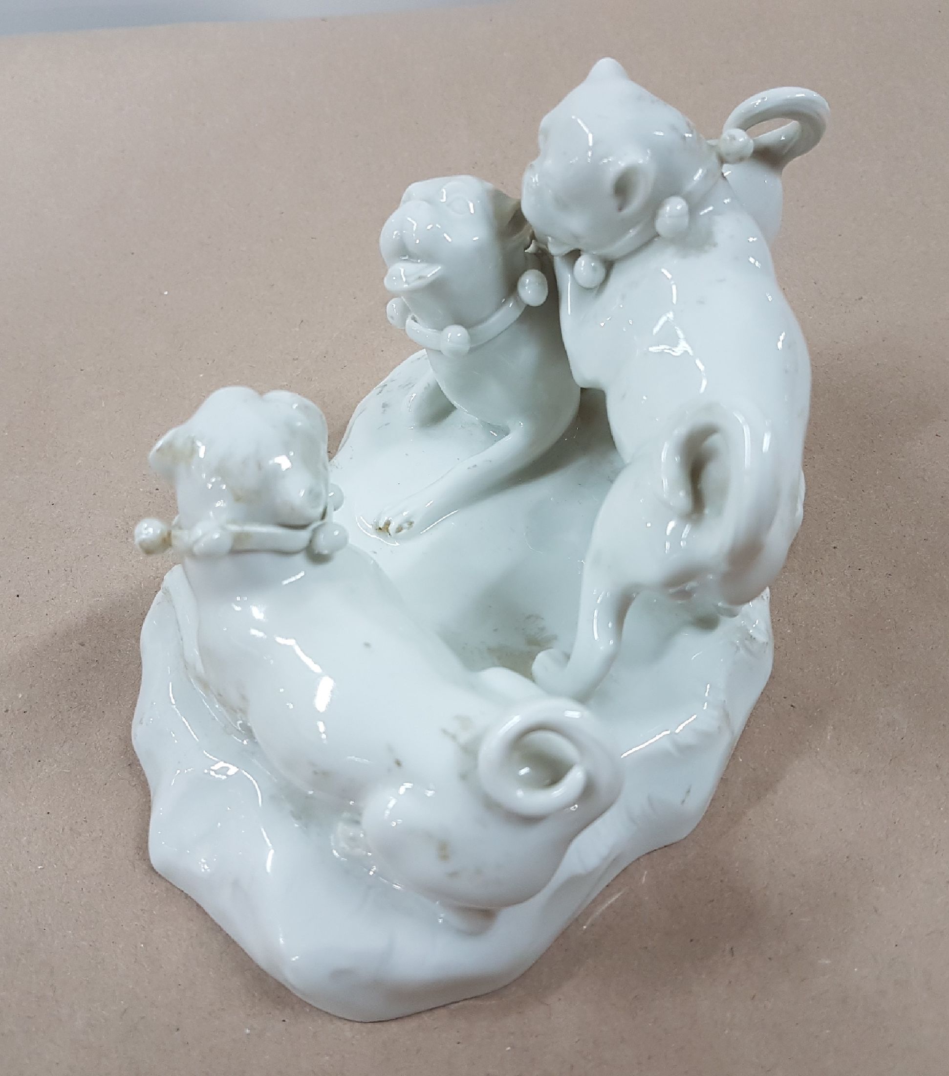 Detail c: Porzellangruppe, Meissen, 20. Jh., weiß, drei spielende Möpse, Entwurf August Ringler, Modellnr. 78836, zwei Schleifstriche,8.5 x 16 x 10 cm, ...