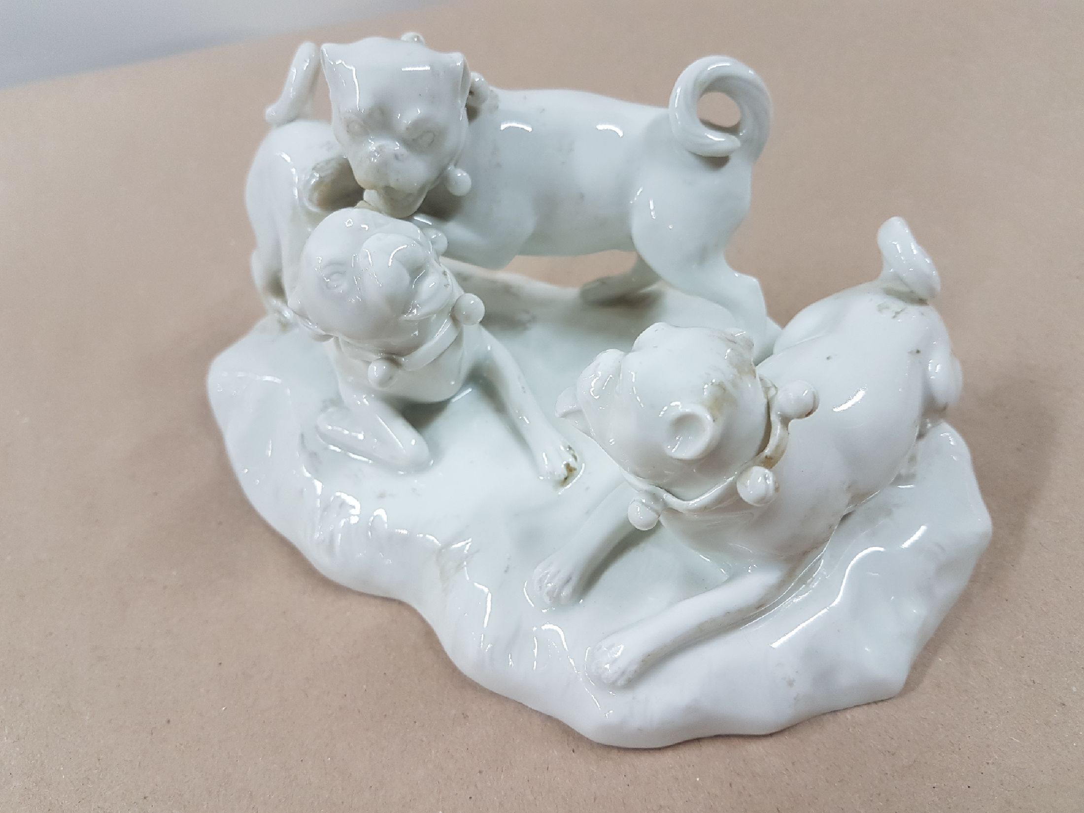 Detail d: Porzellangruppe, Meissen, 20. Jh., weiß, drei spielende Möpse, Entwurf August Ringler, Modellnr. 78836, zwei Schleifstriche,8.5 x 16 x 10 cm, ...