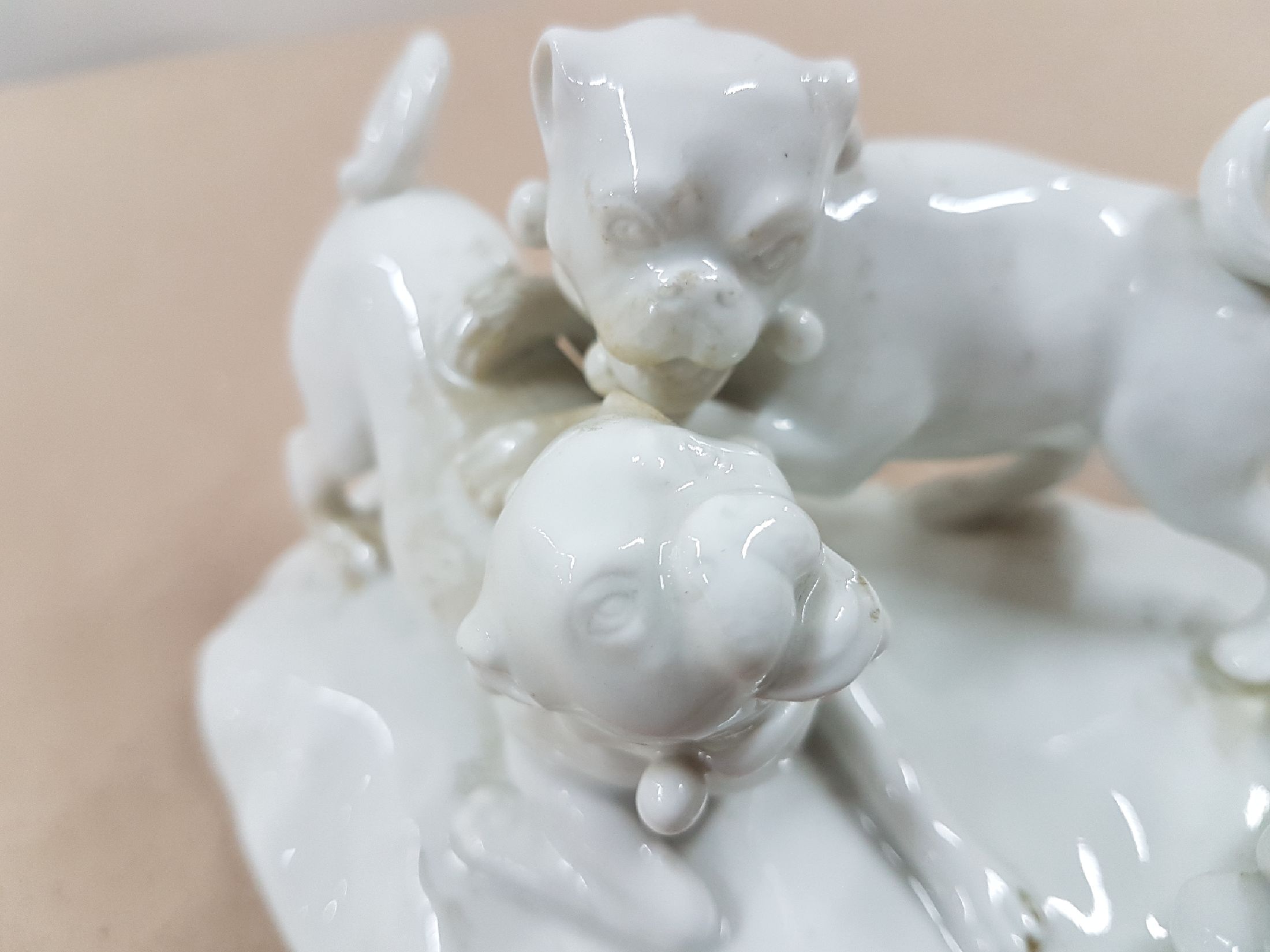 Detail e: Porzellangruppe, Meissen, 20. Jh., weiß, drei spielende Möpse, Entwurf August Ringler, Modellnr. 78836, zwei Schleifstriche,8.5 x 16 x 10 cm, ...