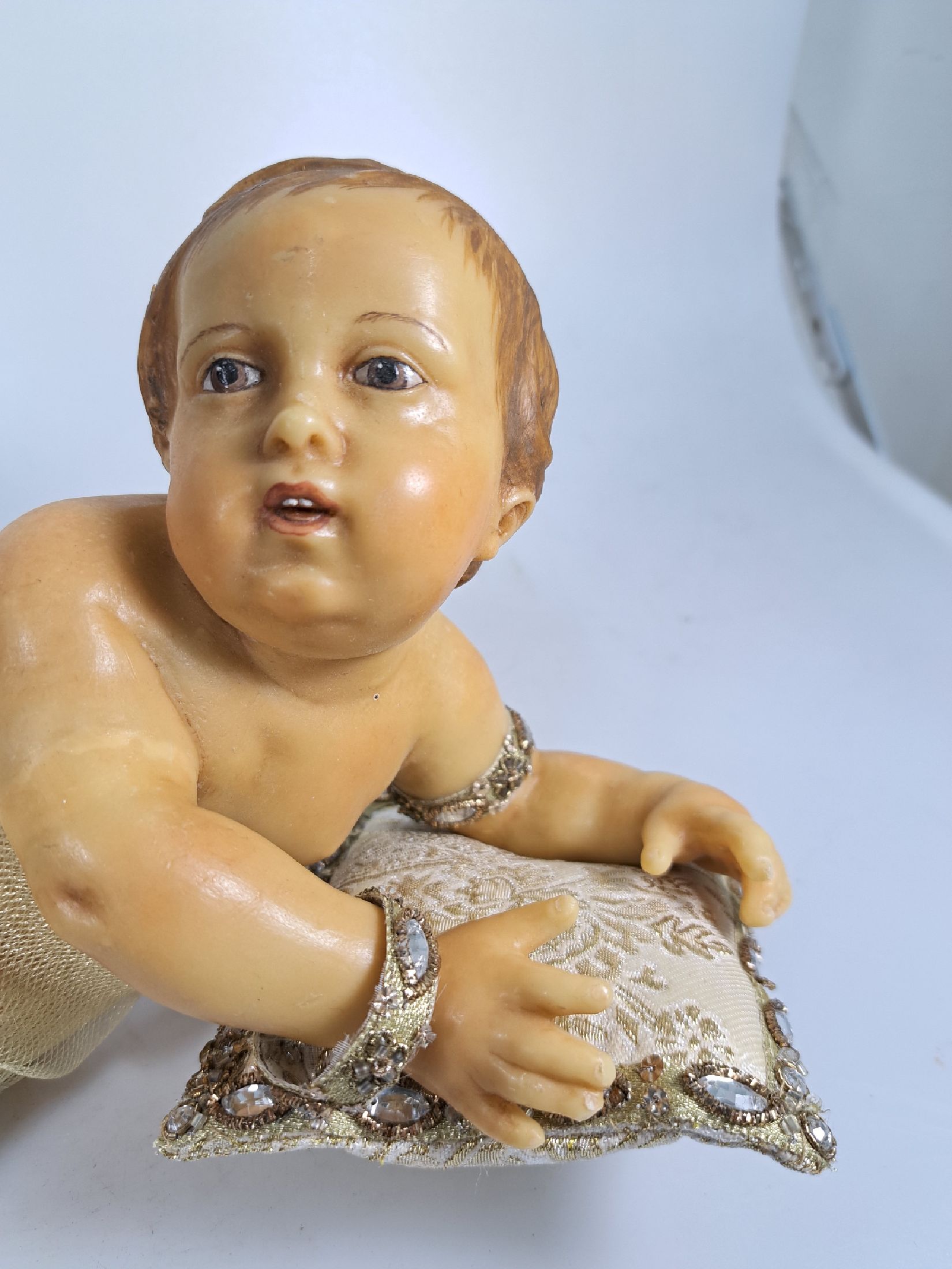 Detail a: Fatschenkind im Glasschrein, süddeutsch, 20.Jh., Wachskorpus wohl 19.Jh., Bekleidung und Auskleidung mit Spitzenbesatz und Goldbrokatstickerei, ...