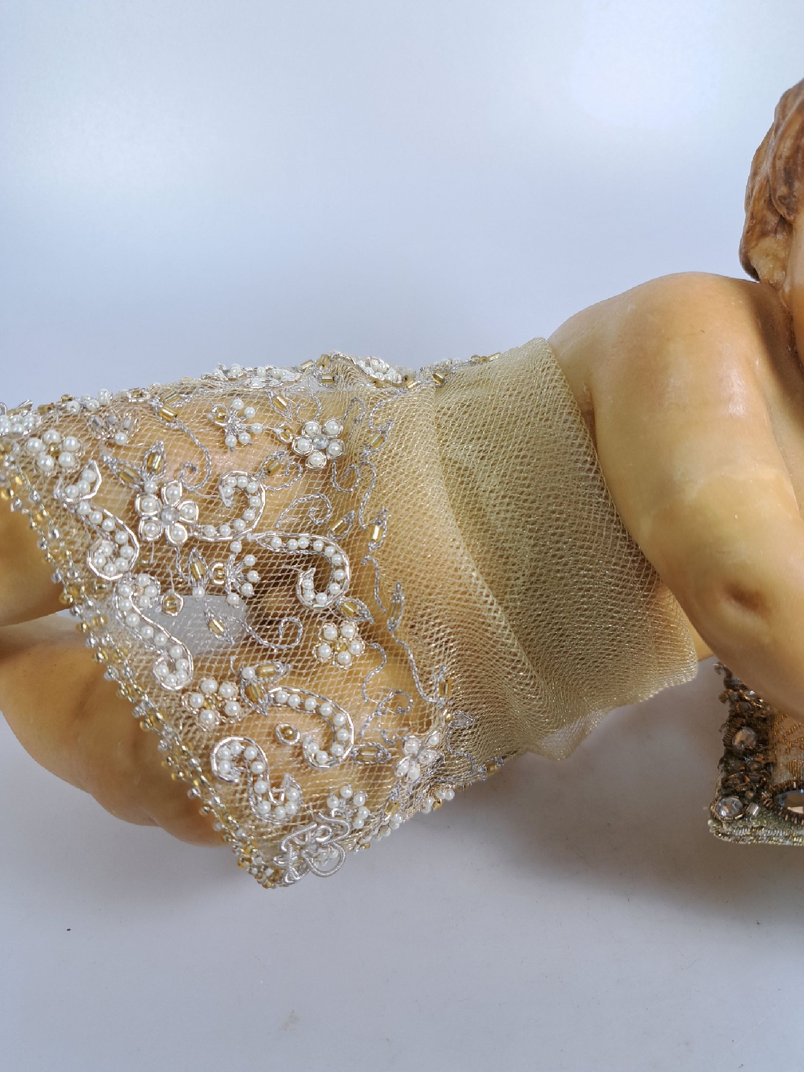 Detail b: Fatschenkind im Glasschrein, süddeutsch, 20.Jh., Wachskorpus wohl 19.Jh., Bekleidung und Auskleidung mit Spitzenbesatz und Goldbrokatstickerei, ...