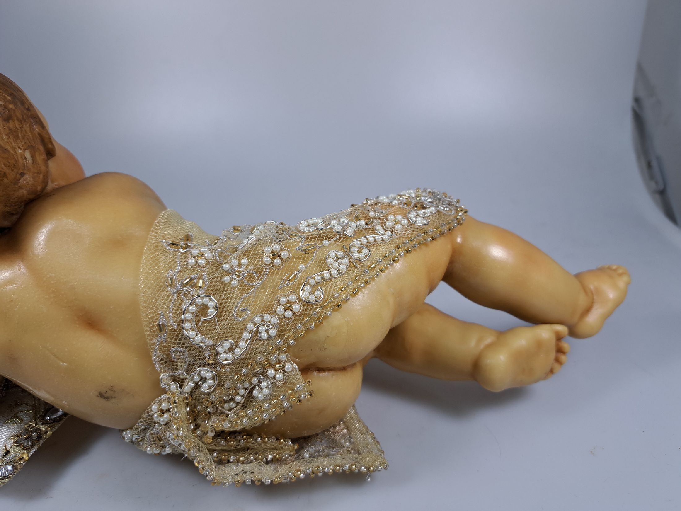 Detail g: Fatschenkind im Glasschrein, süddeutsch, 20.Jh., Wachskorpus wohl 19.Jh., Bekleidung und Auskleidung mit Spitzenbesatz und Goldbrokatstickerei, ...
