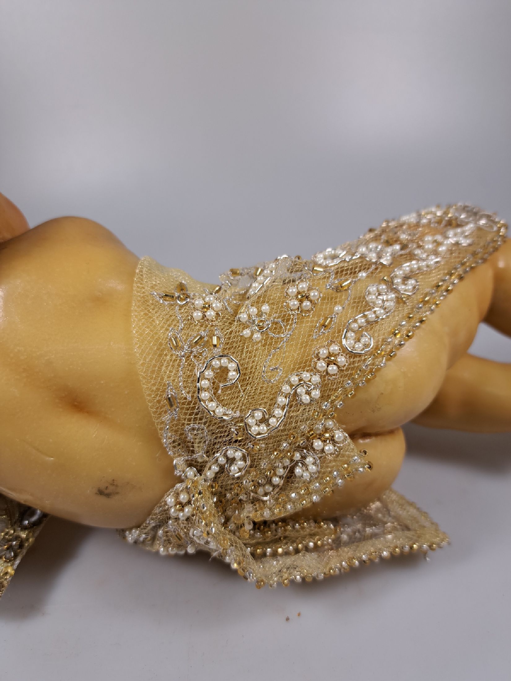 Detail i: Fatschenkind im Glasschrein, süddeutsch, 20.Jh., Wachskorpus wohl 19.Jh., Bekleidung und Auskleidung mit Spitzenbesatz und Goldbrokatstickerei, ...