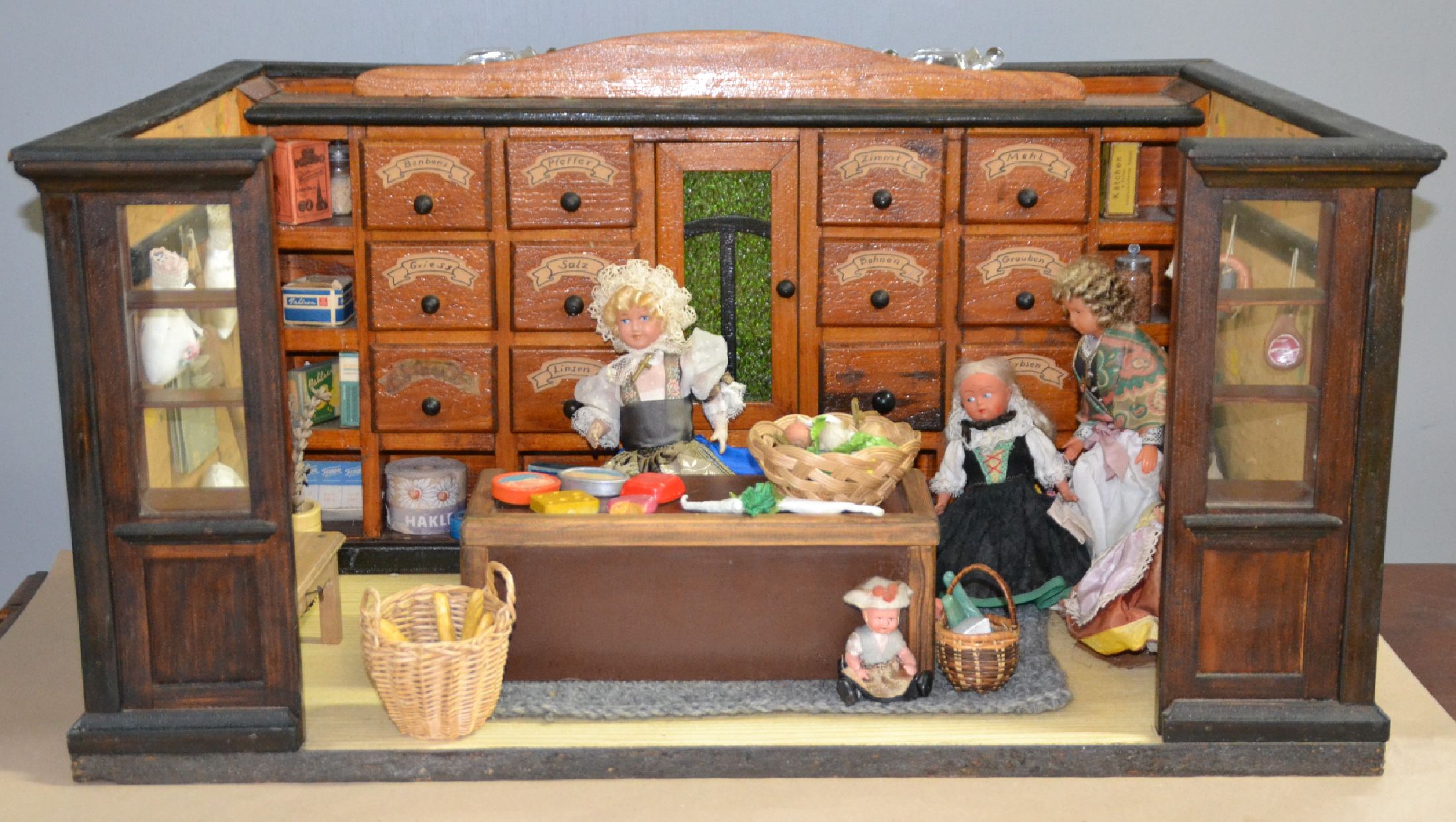 Kaufladen, deutsch, um 1915, Holzgehäuse, Holzgalerie mit Tür und beschrifteten Schubläden (Salz, Bohnen, Mehl usw.), Holztheke, Hängeschränke, ...
